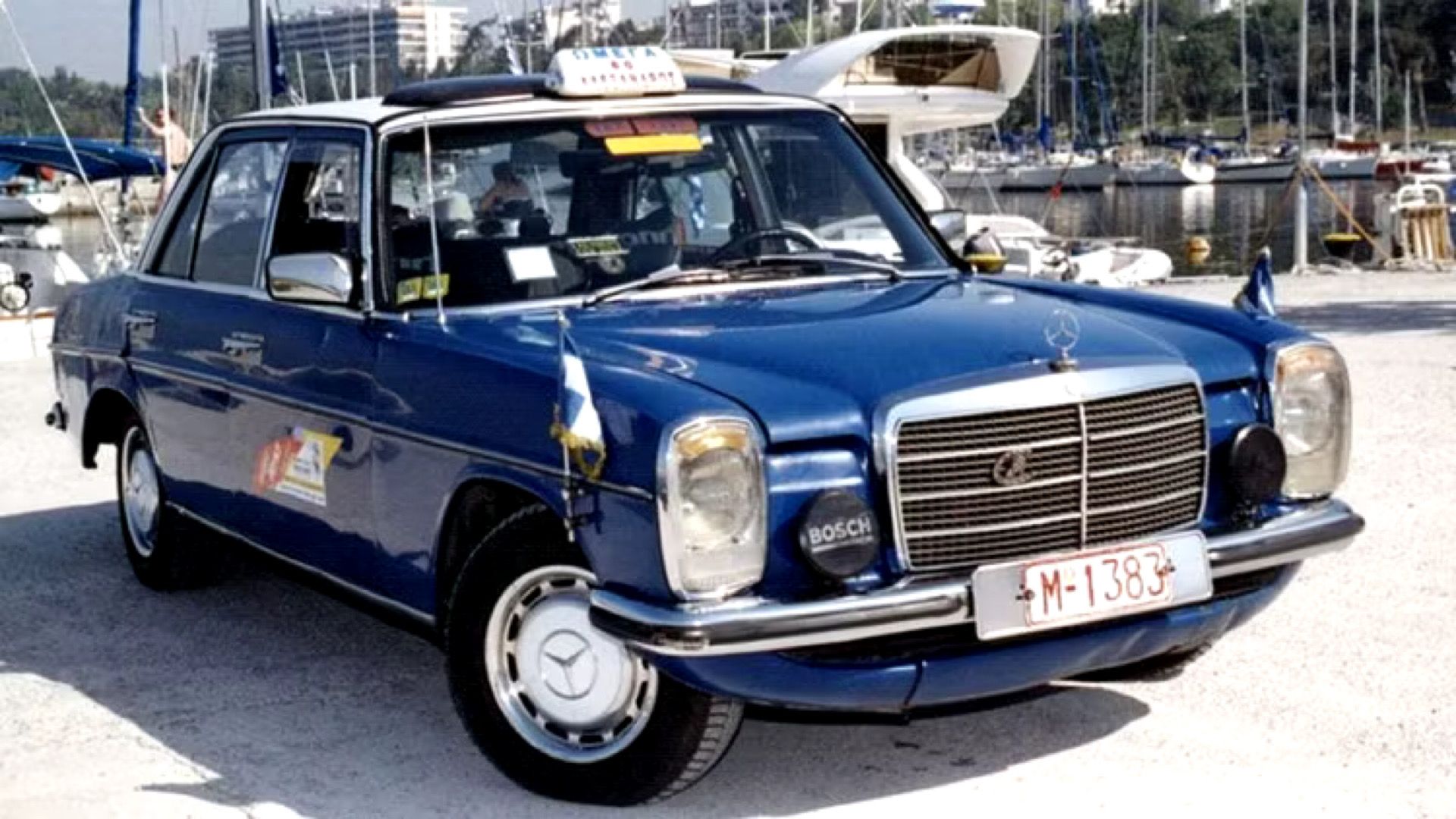 1976 Mercedes-Benz 240D in blue posing in harbour in front of boats