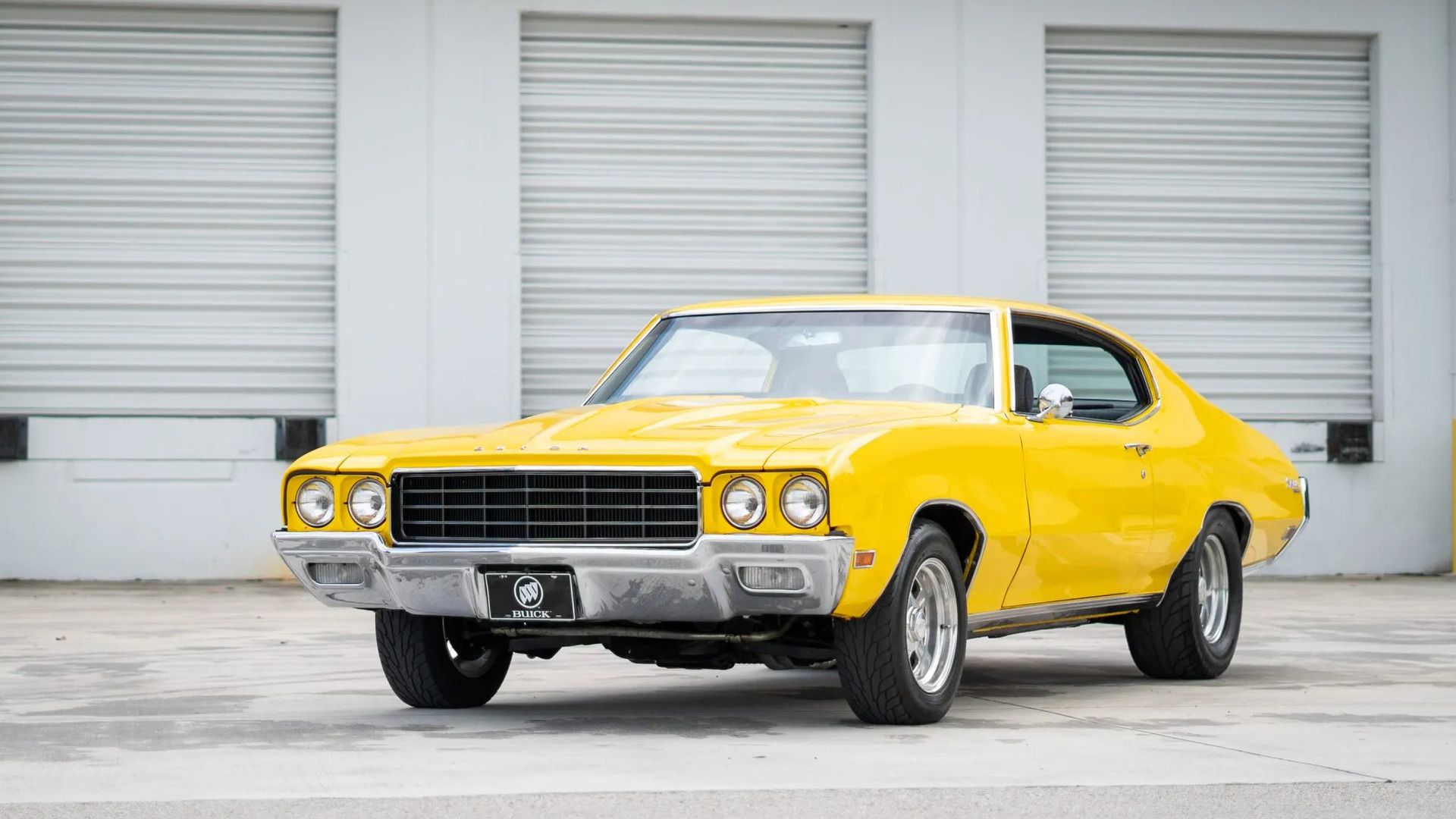 1970 Buick Skylark Coupe yellow parked in front of a warehouse