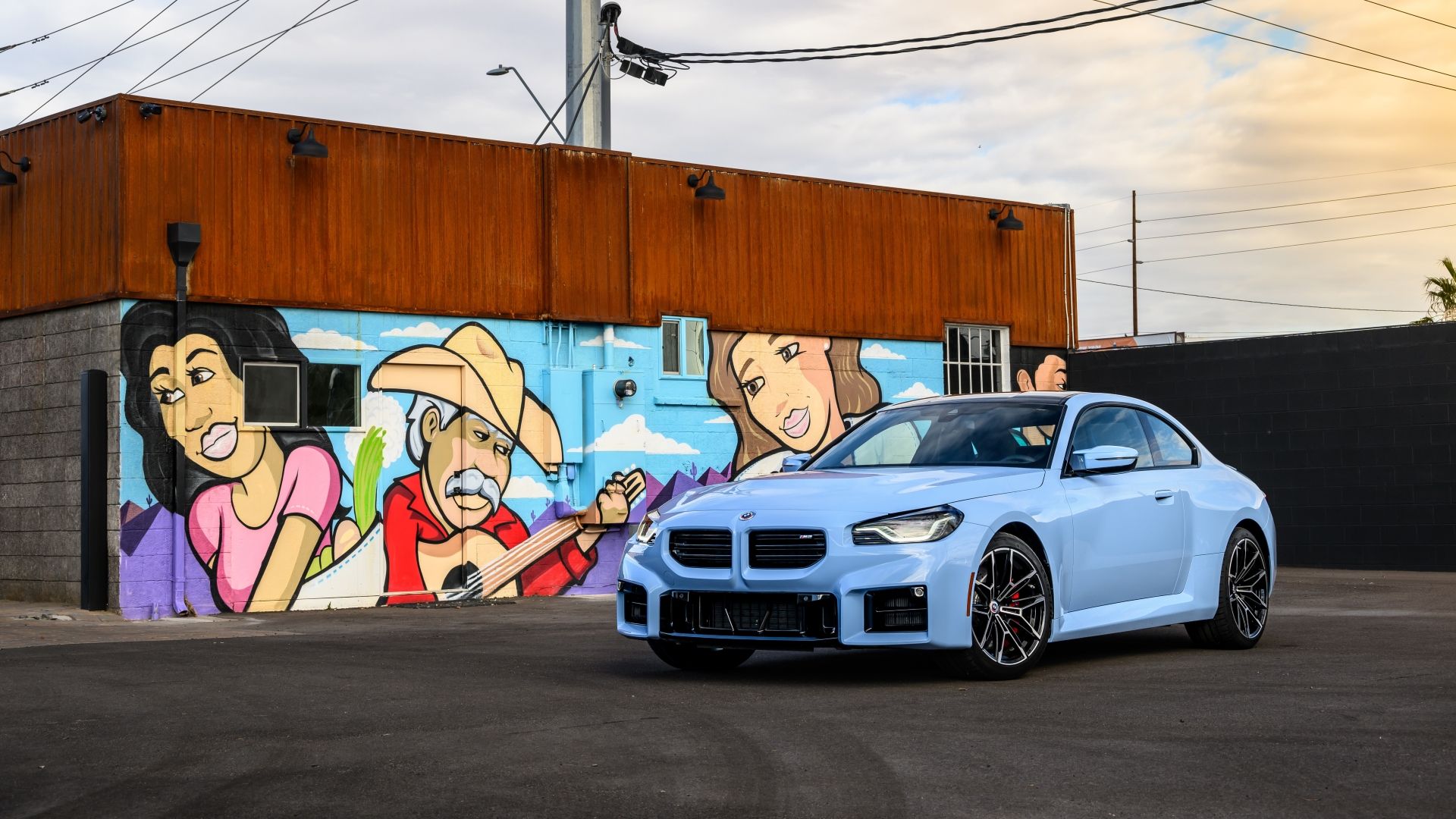 Front 3/4 shot of a 2024 BMW M2 parked in front of a mural