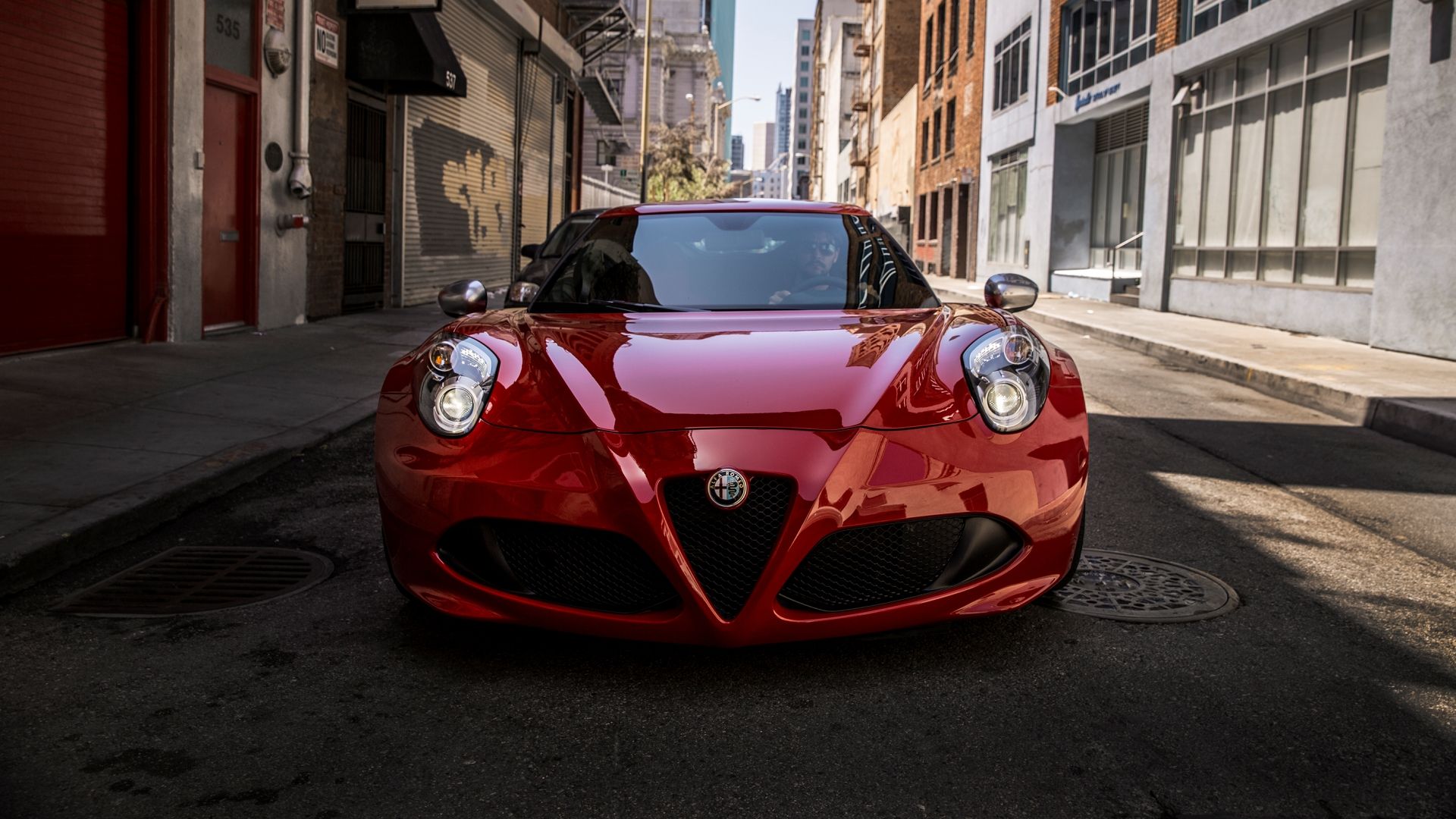 A red 2015 Alfa Romeo 4C Coupe front shot driving on a city street