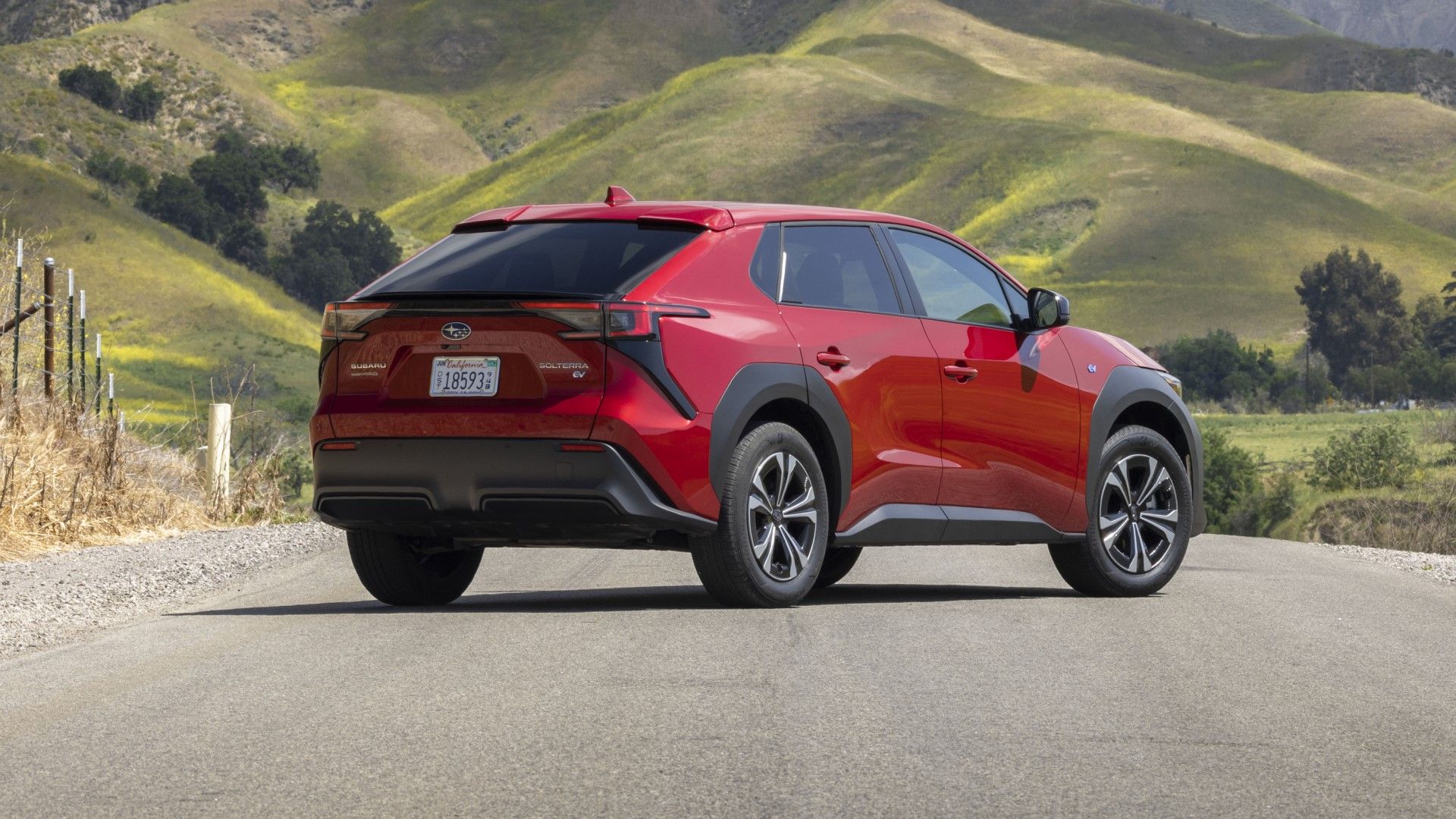 Uma foto estática da frente de um Subaru Solterra vermelho estacionado no campo