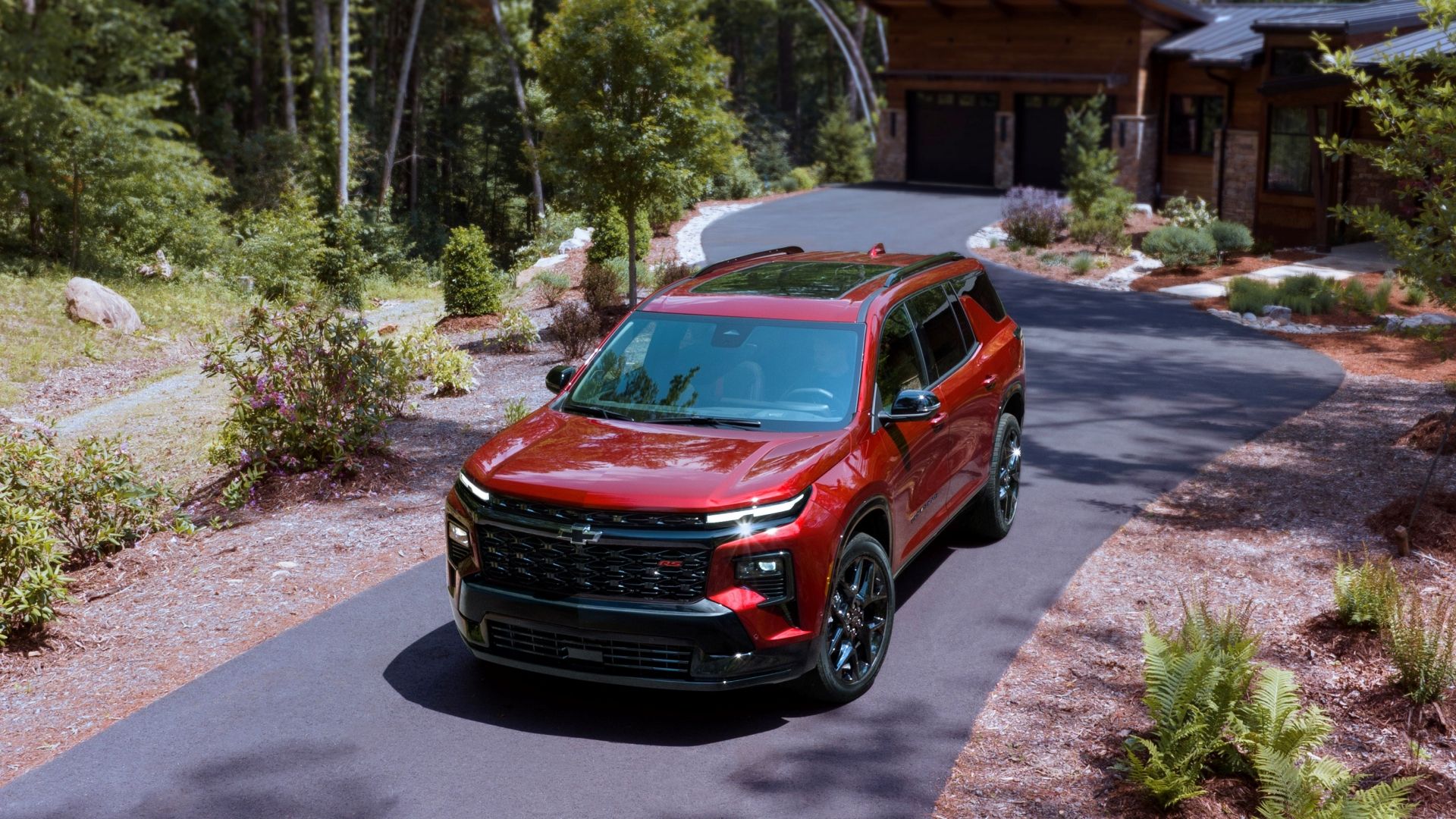 A Red 2024 Chevrolet Traverse RS parked on a driveway, seen from the front
