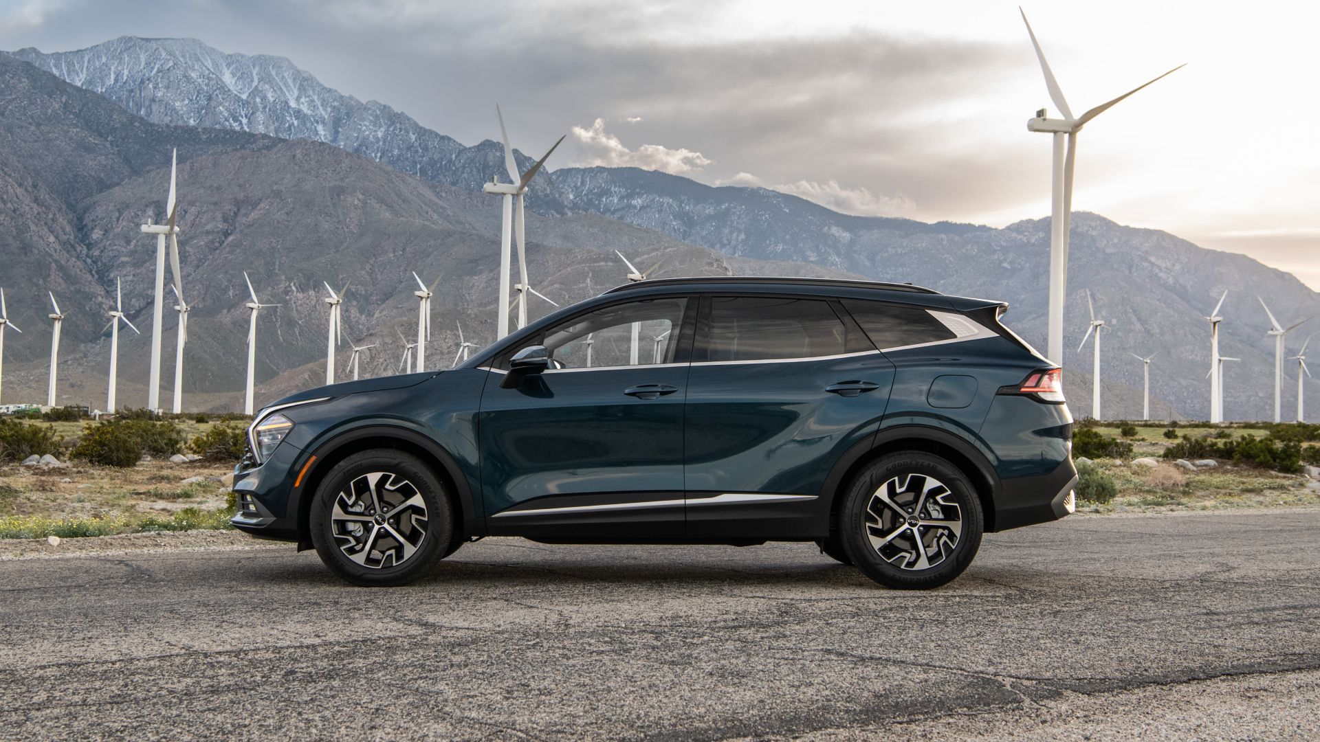 Side profile shot of a 2024 Kia Sportage Hybrid parked in front of the windmills