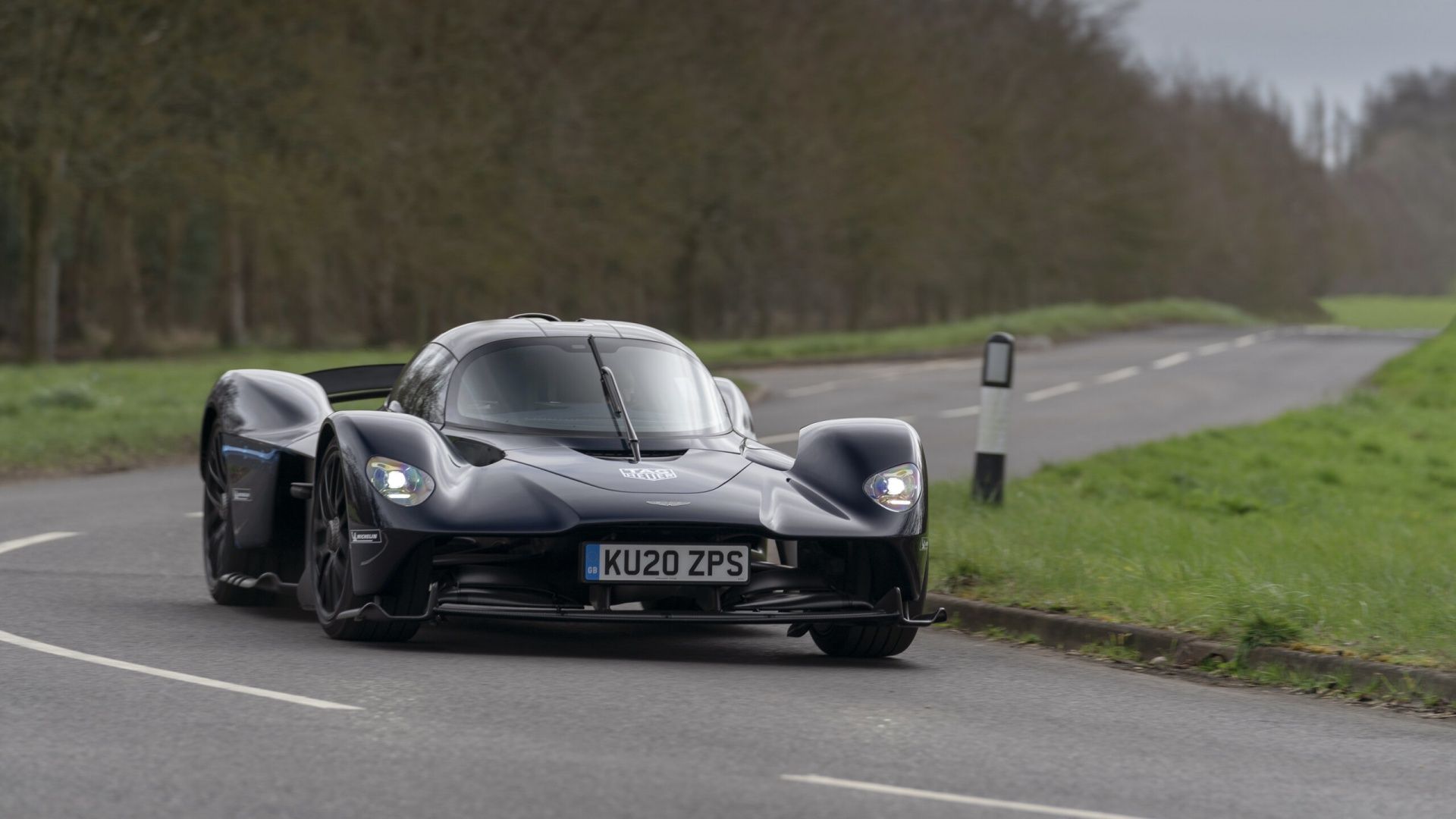 Aston Martin Valkyrie in black front end shot driving on a two lane road