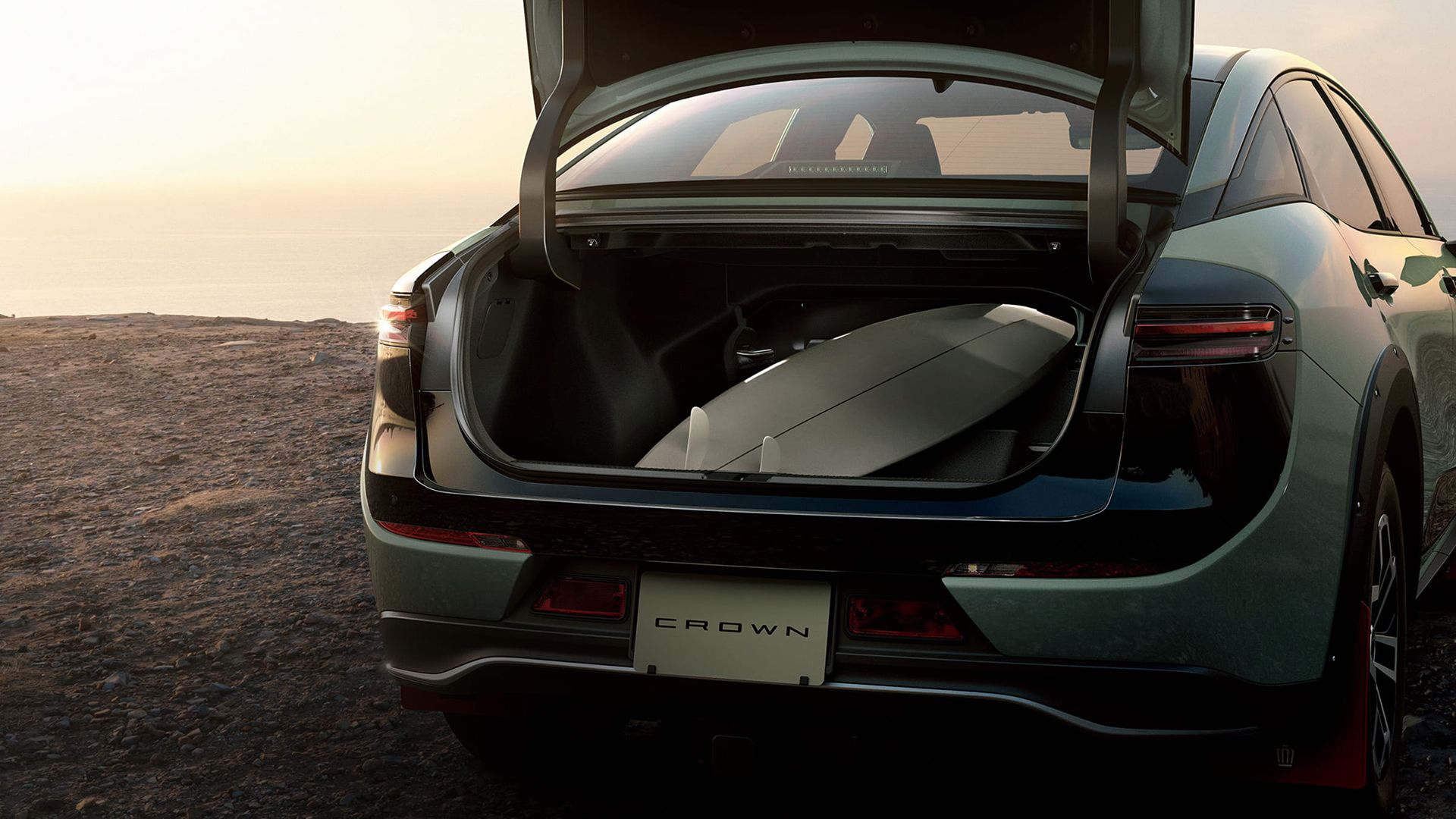 2024 Toyota Crown Landscape parked on a beach, showing the rear end with trunk open. 