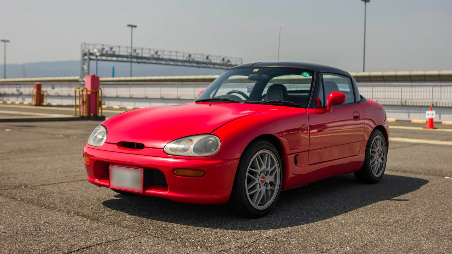 Cappuccino Suzuki 1993 vermelho com capota rígida preta estacionada na frente 3/4 vista
