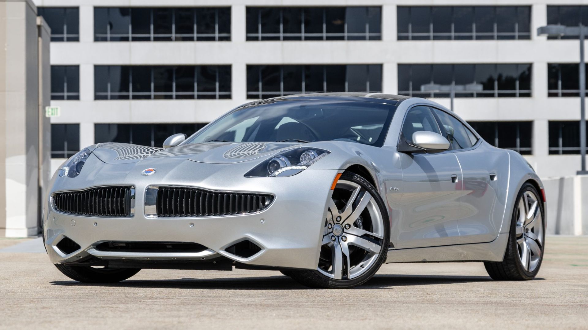 2012 Fisker Karma pintado de vento prateado estacionado de lado.