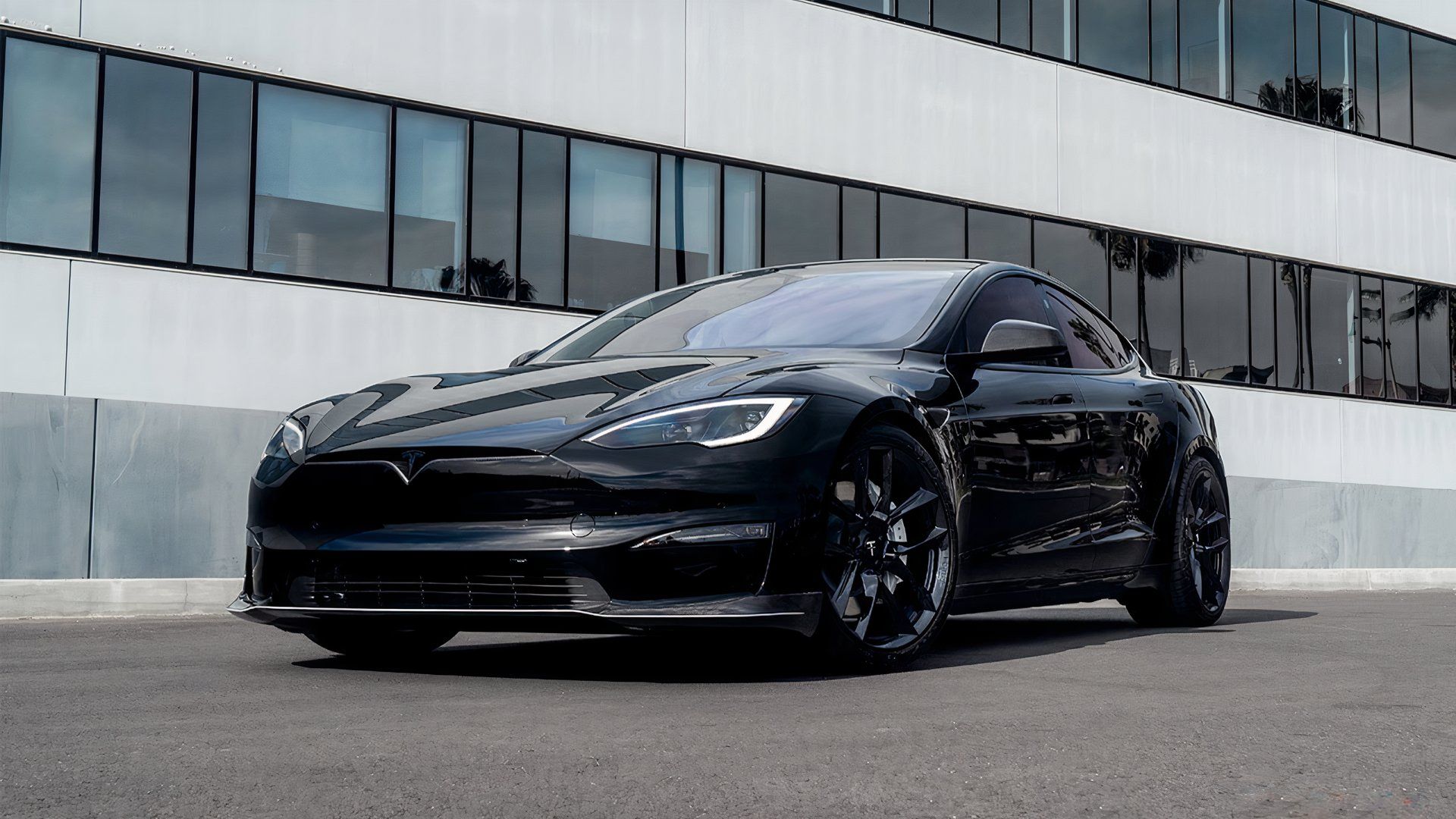 A static front-quarter shot of a black Tesla Model S Anniversary Edition parked at TSportline's factory.