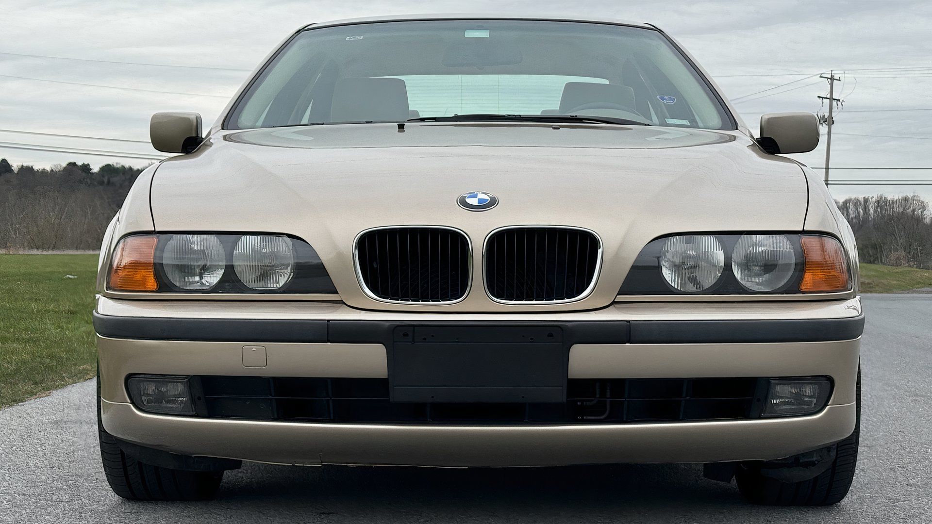 1999 BMW E39 M5 na frente bege Mostrando grade em forma de rim, faróis, pára-choque e emblema da BMW