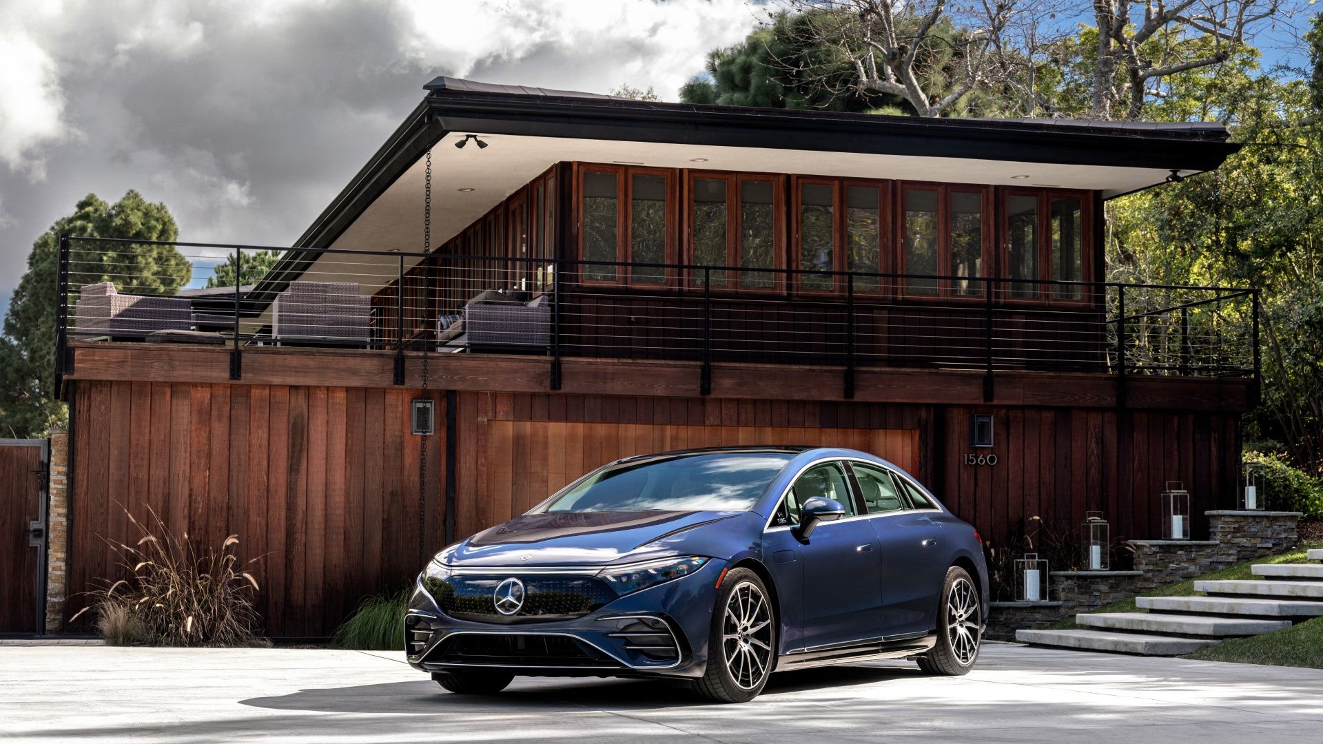 Blue Mercedes EQS parked Outside a modern home