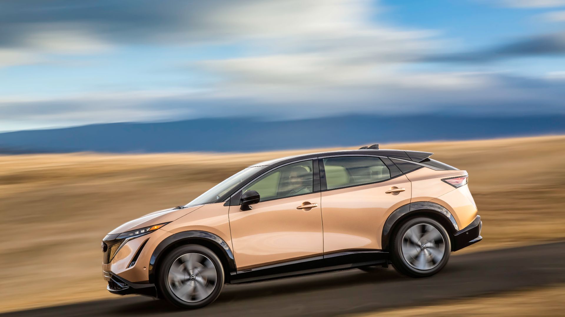 2023 Nissan Ariya driving down a road. 
