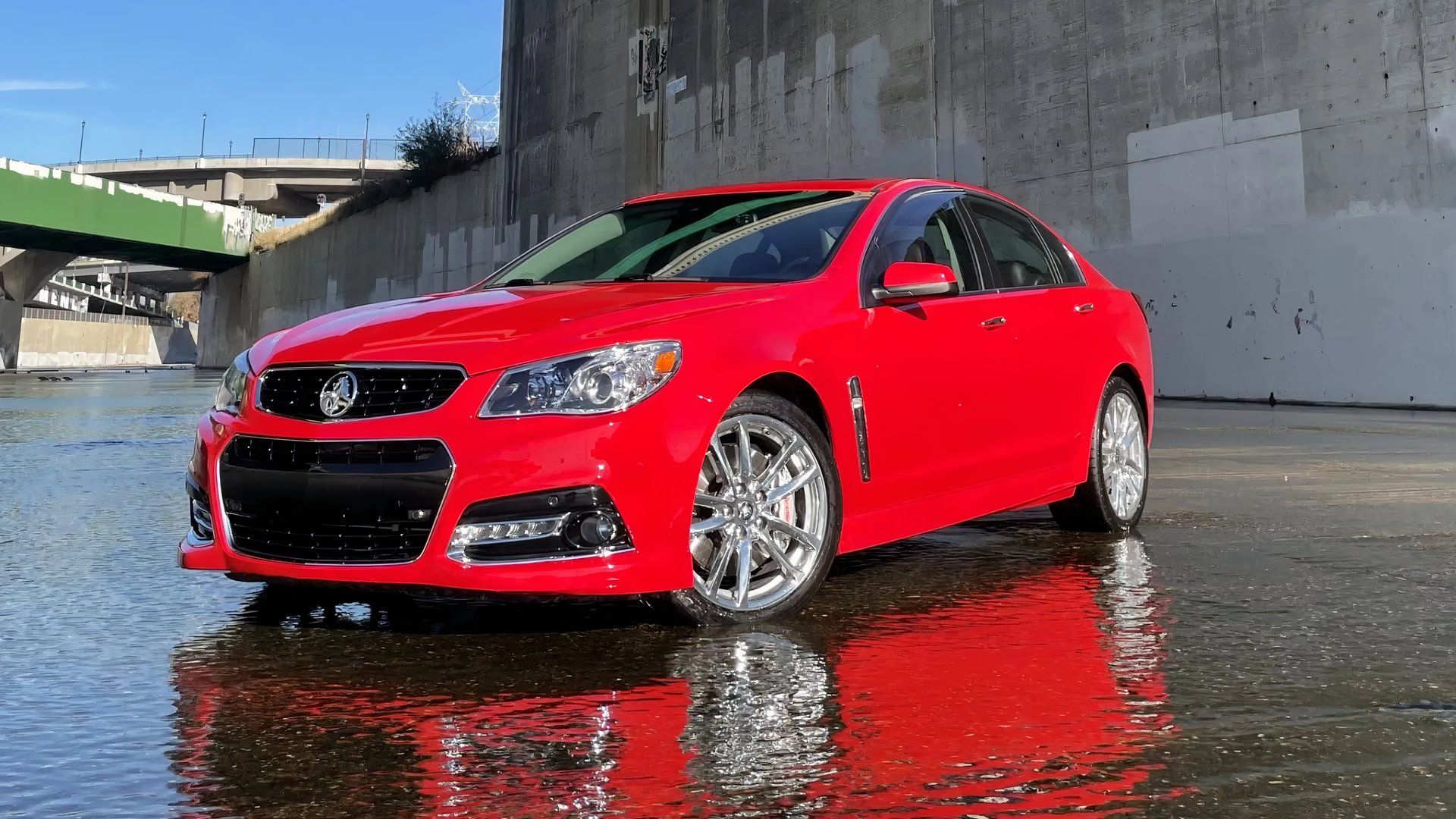 Uma foto externa 3/4 frontal vermelha do Chevrolet SS Sedan 2014 estacionada em um aqueduto.