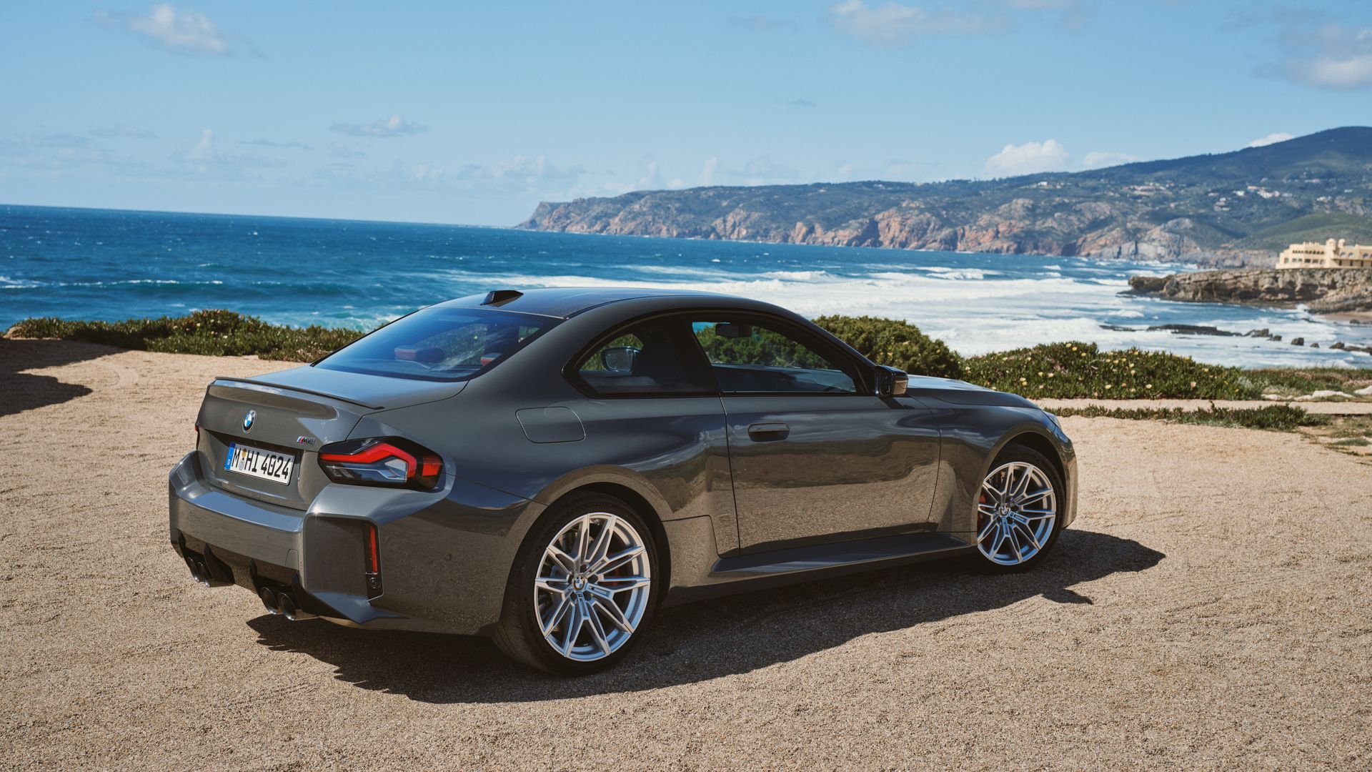 2025 BMW M2 rear 3/4 exterior shot, parked overlooking the ocean on a sunny day.