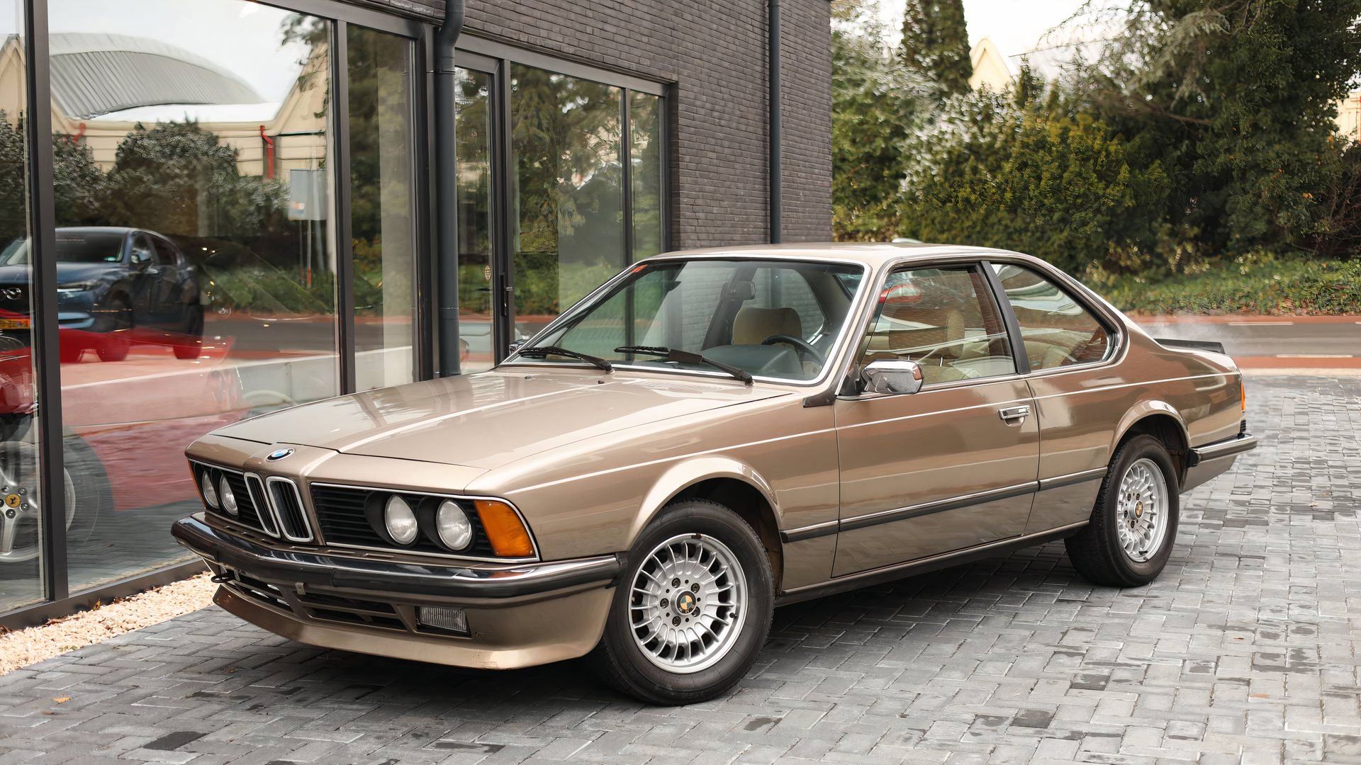 BMW 635CSI Classic dourado de 1984 estacionado em frente à loja 