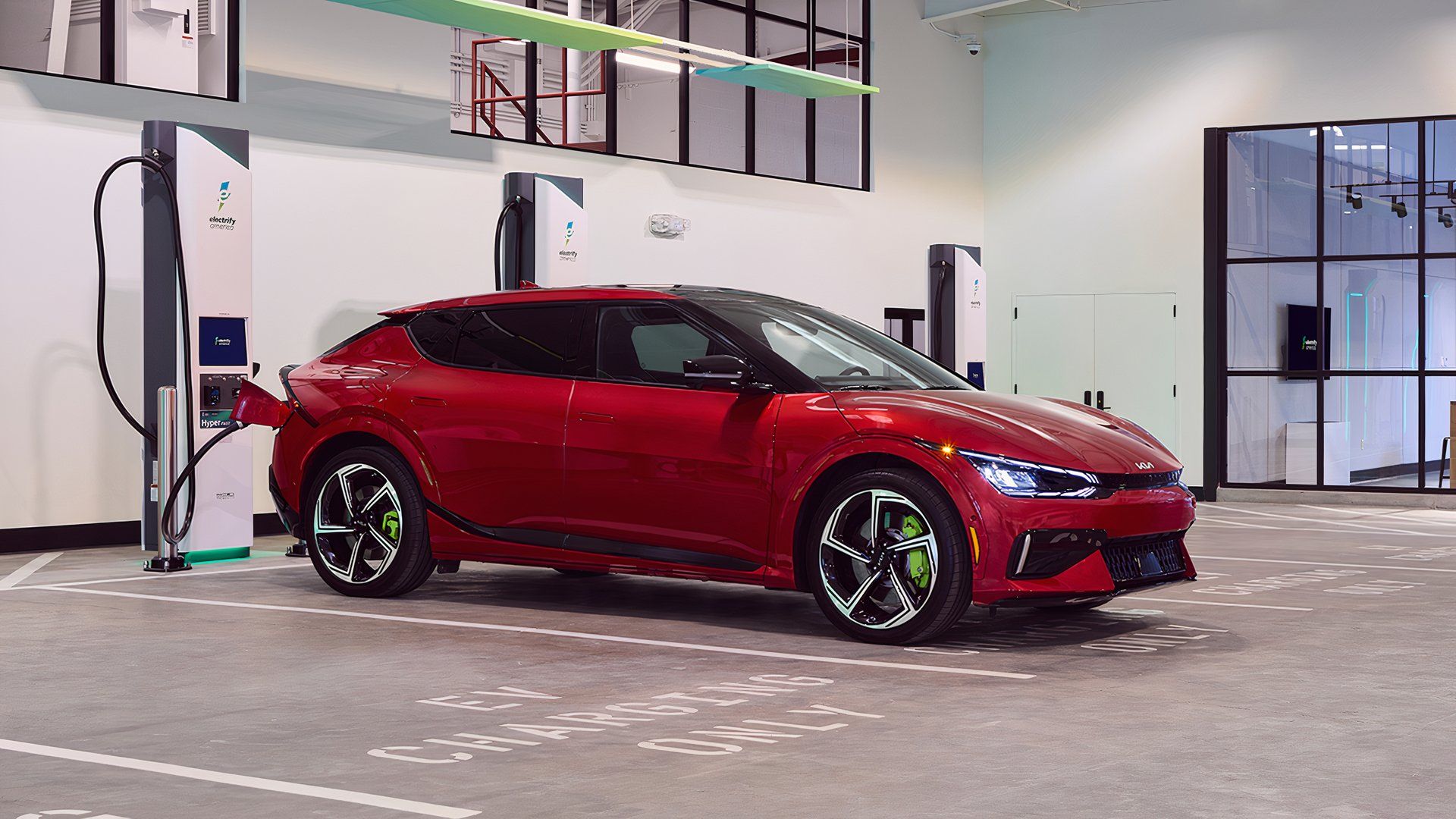 Kia EV6 vermelho conectado a uma estação de carregamento Electrify America em ambientes fechados