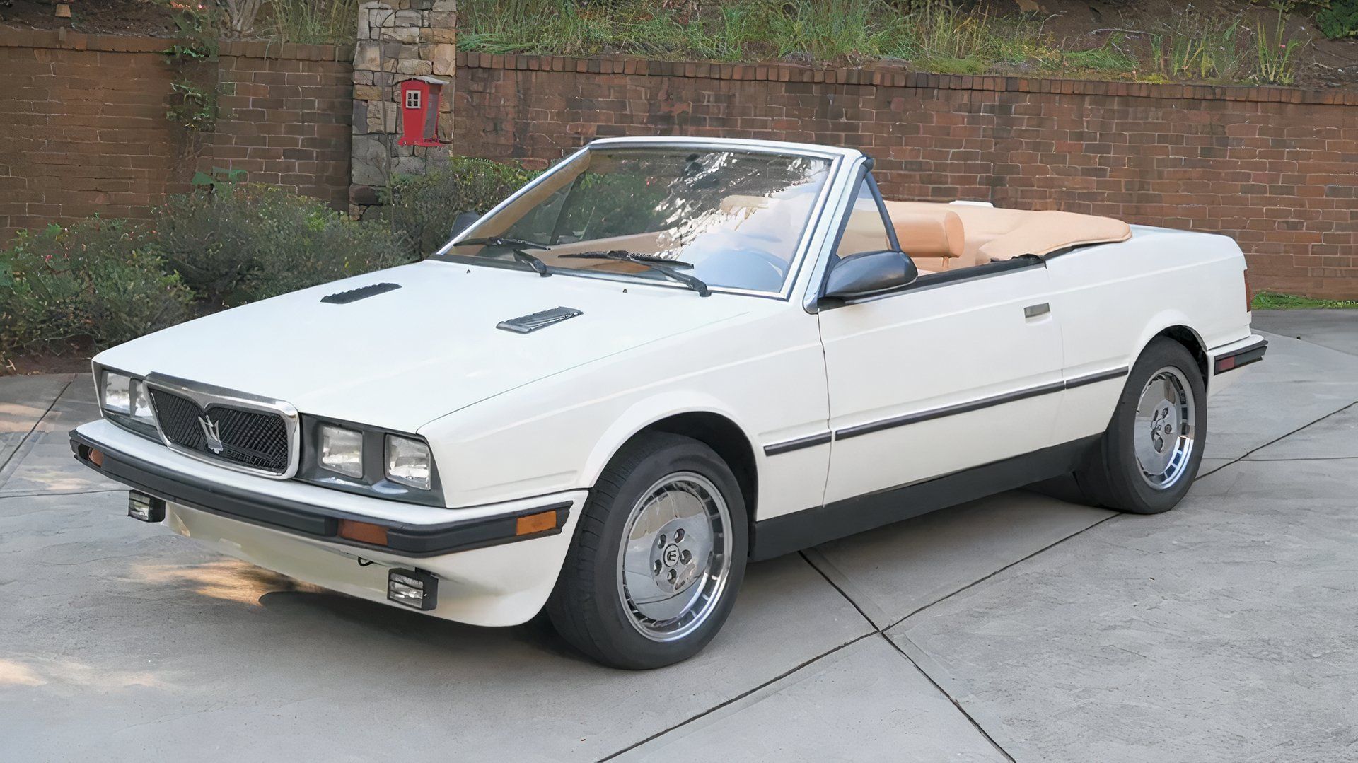 Maserati Biturbo Spyder branco de 1989 estacionado em frente à cerca 