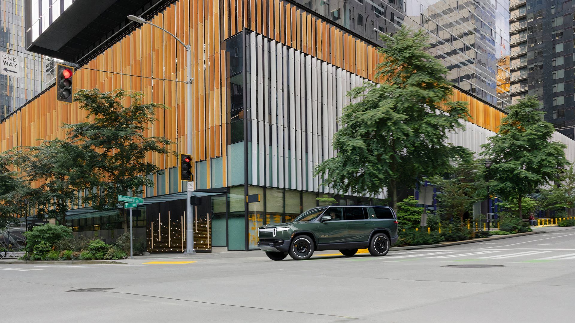 Um SUV elétrico familiar verde Rivian R1S 2025 está circulando na estrada. 
