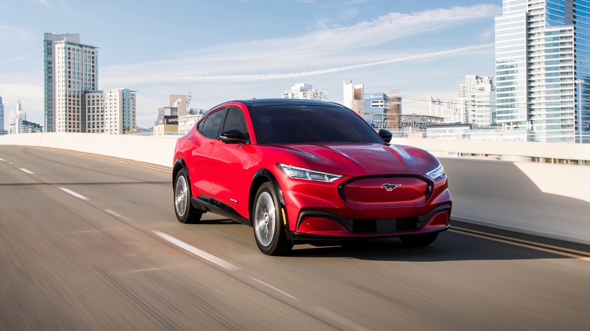 2021 Mustang Mach E in red driving shot through downtown