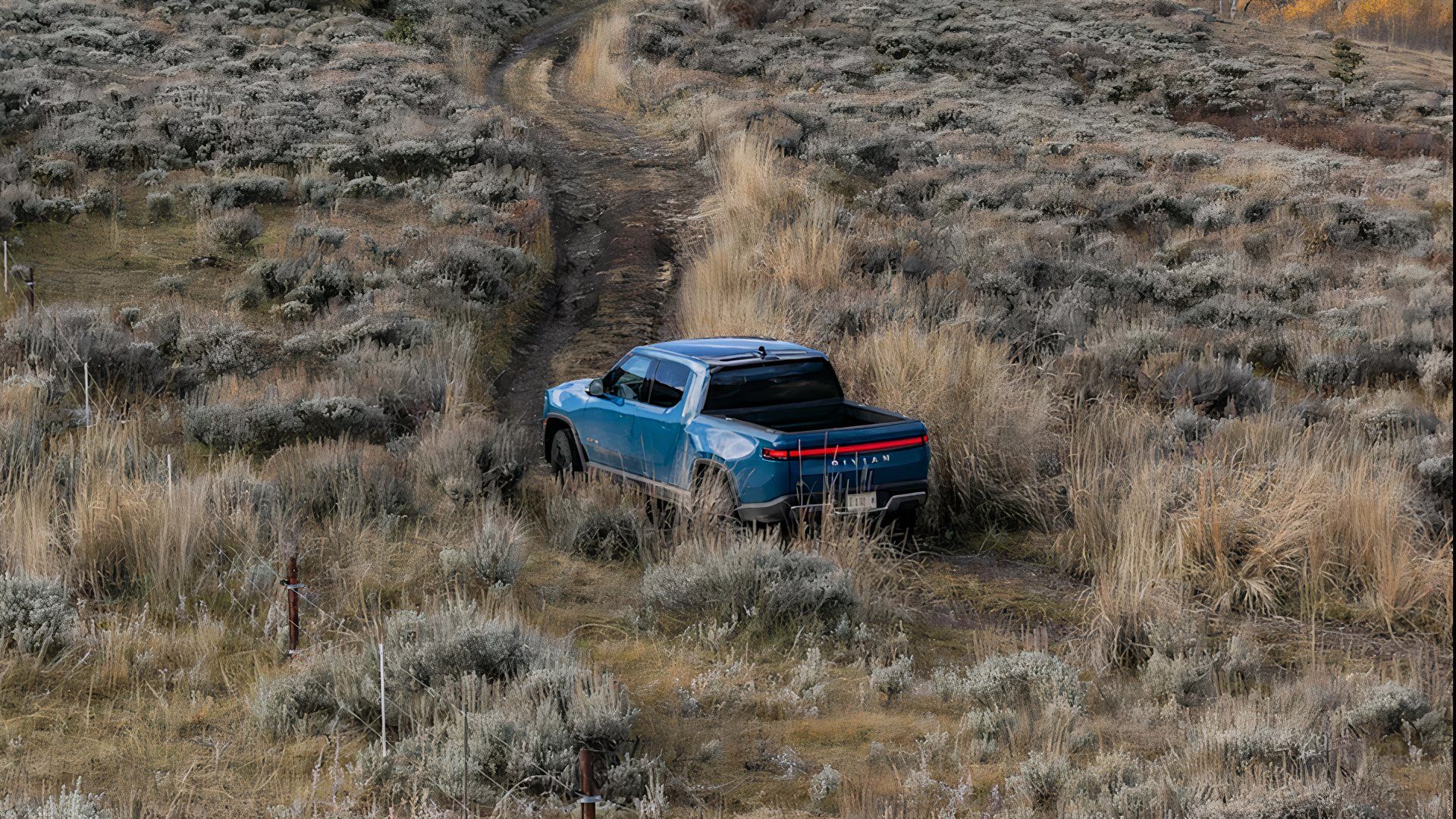Uma picape elétrica Rivian R1T 2025 azul Rivian está viajando off-road. 