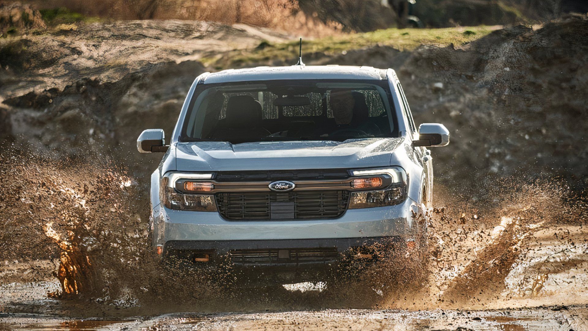 A blue 2023 Ford Maverick pickup truck drives off-road. 