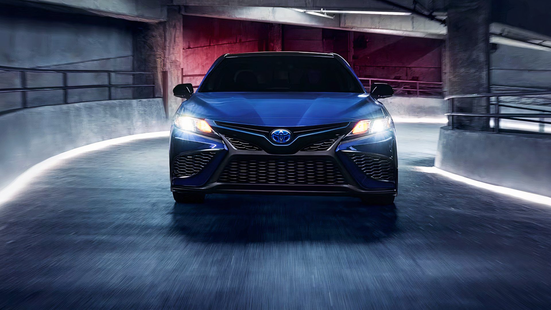 A blue 2024 Toyota Camry Hybrid is driving. 