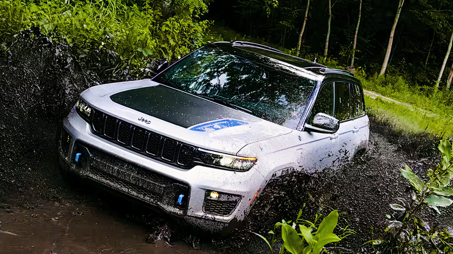 A white Jeep Grand Cherokee 4xe is driving off-road. 