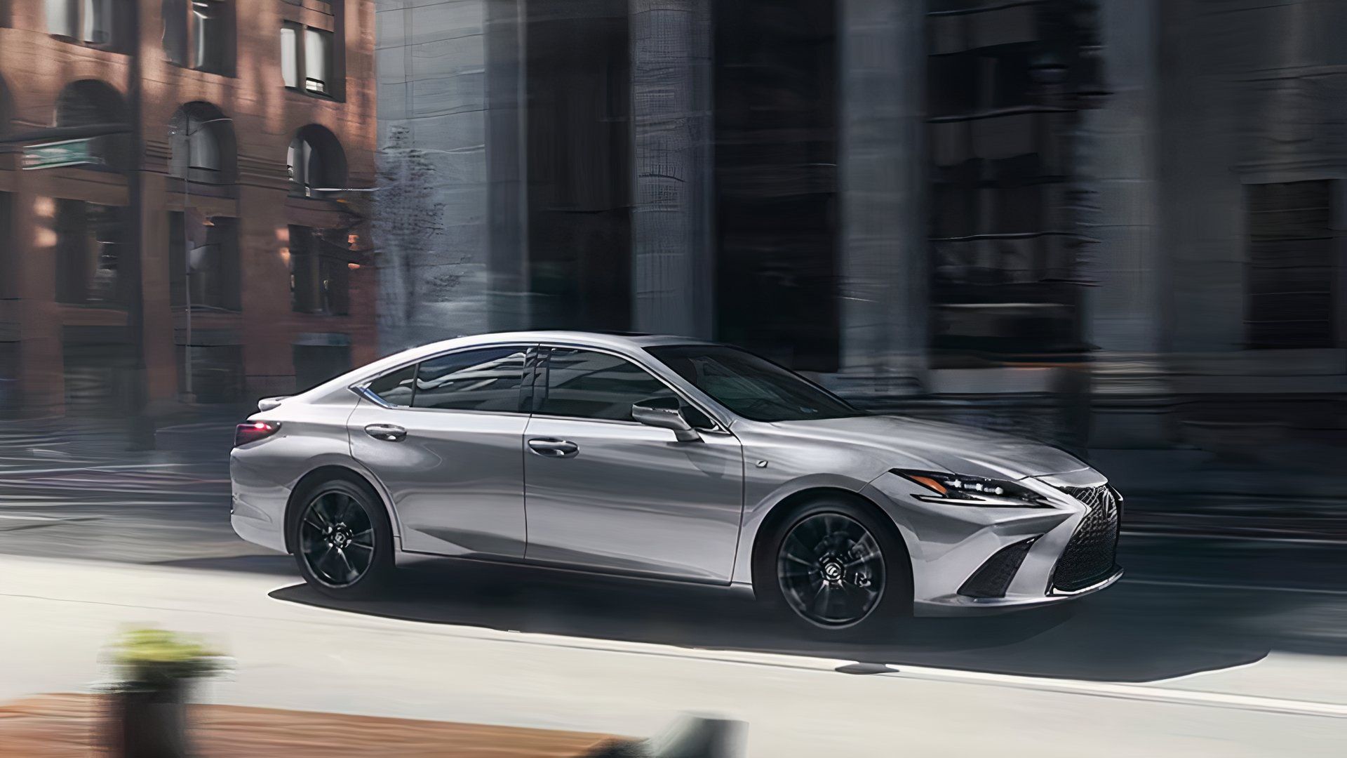 Um Lexus ES Hybrid 2025 prata está dirigindo. 