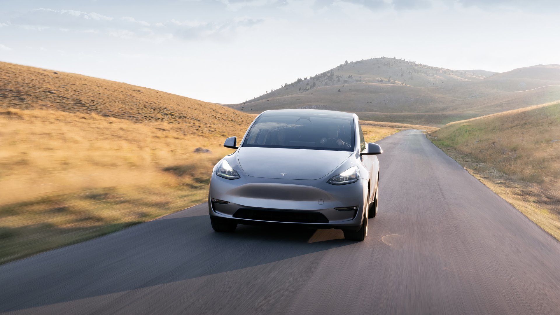 Um Tesla Model Y cinza está dirigindo na estrada. 