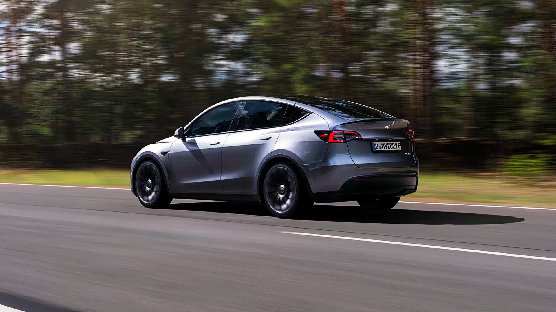 Um Tesla Model Y cinza está dirigindo na estrada. 