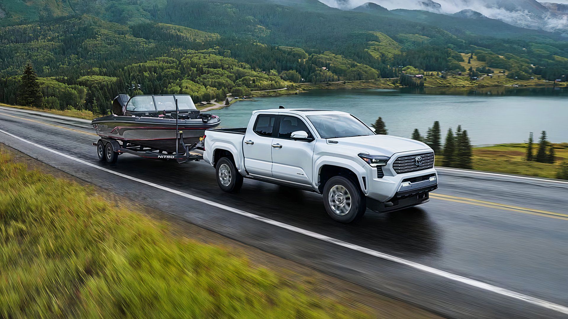 Um Toyota Tacoma Hybrid branco está rebocando um barco. 