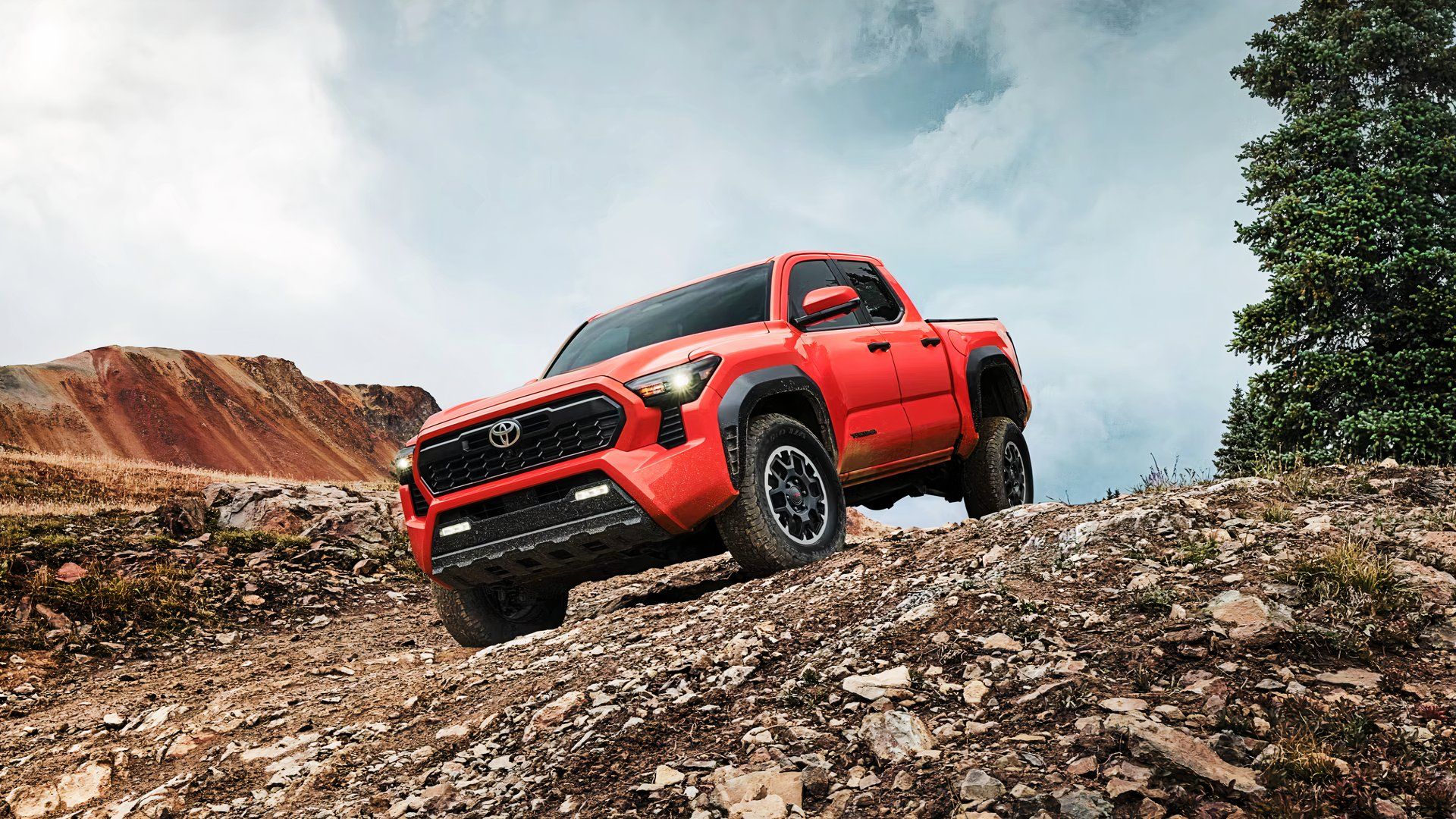 A red Toyota Tacoma i Force Hybrid Max is parked on a hill. 