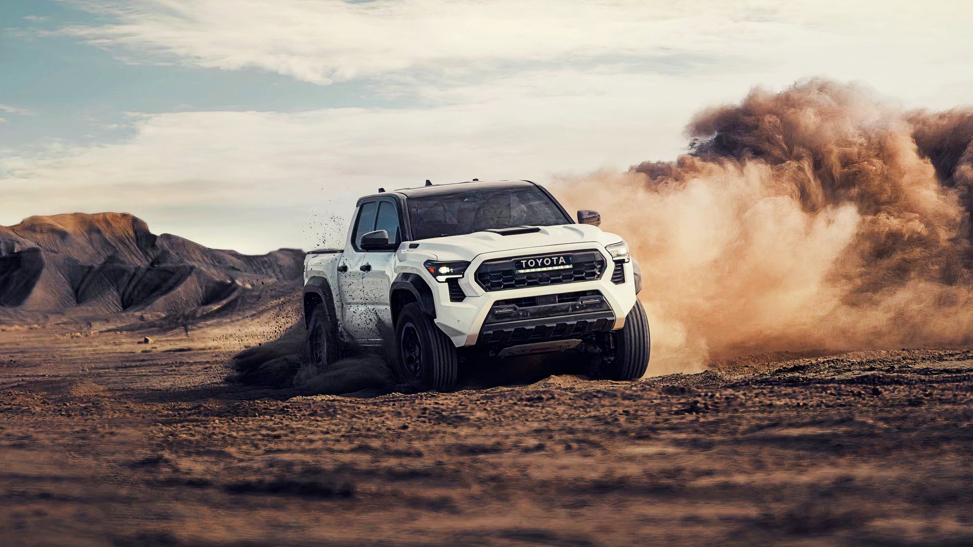 A white Toyota Tacoma i Force Max drives off-road. 