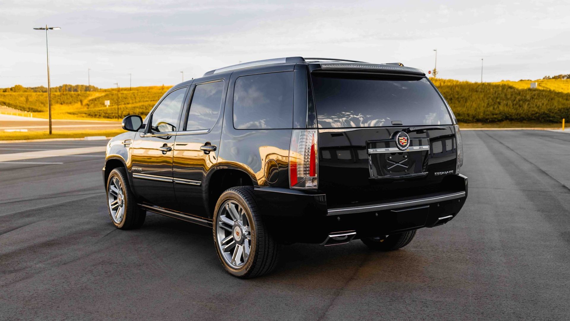 Foto traseira de três quartos de um Cadillac Escalade preto 2014