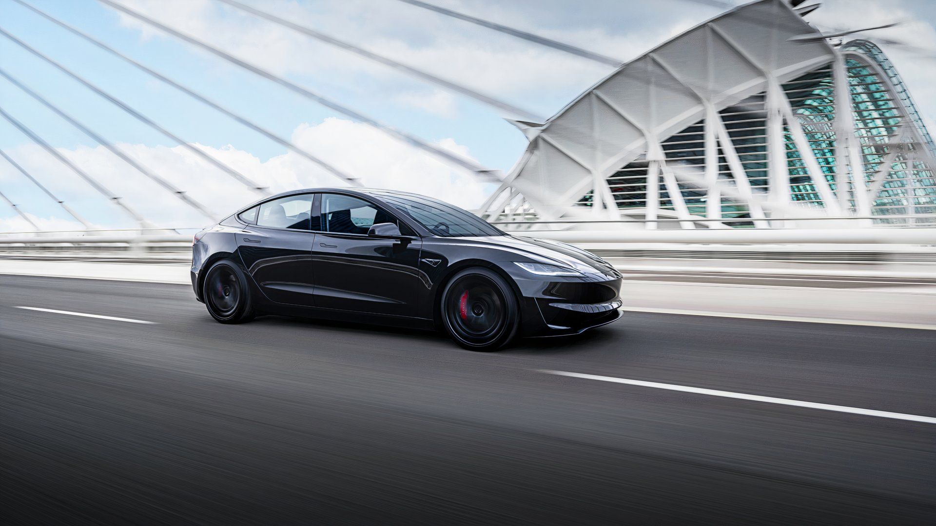A black 2024 Tesla Model 3 Performance is driving on the road. 