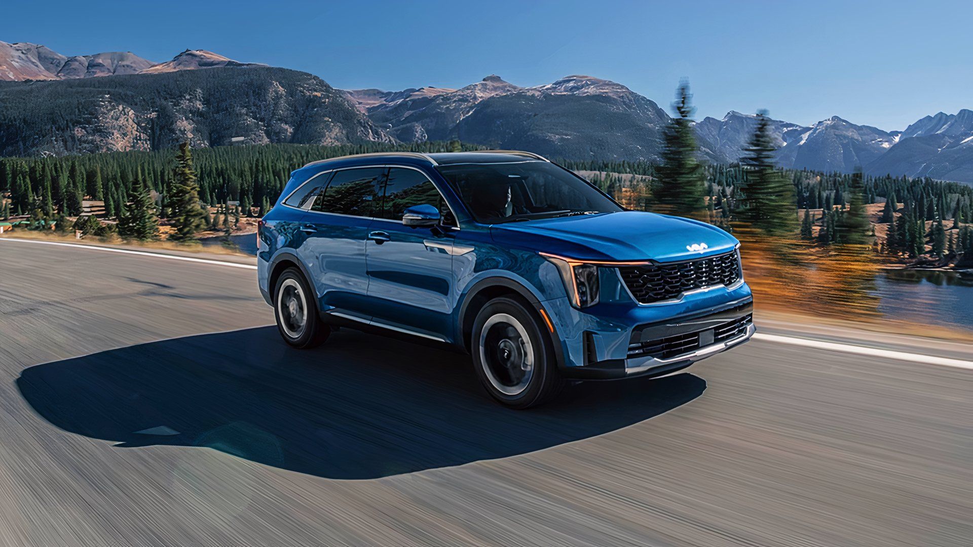 A blue 2025 Kia Sorento Hybrid midsize hybrid SUV is driving on the road. 