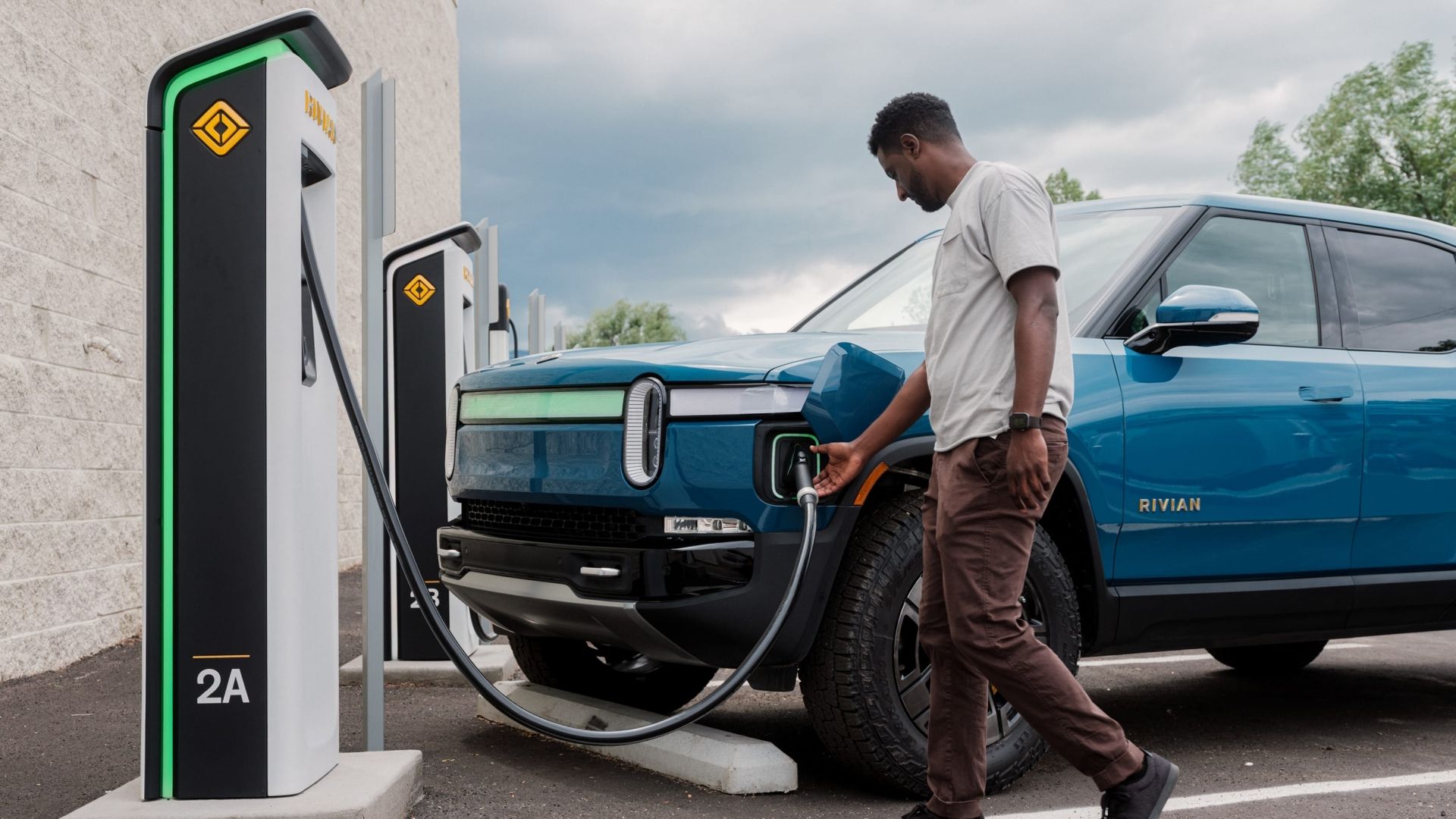 A man charging a Rivian EV at a fast-charging station