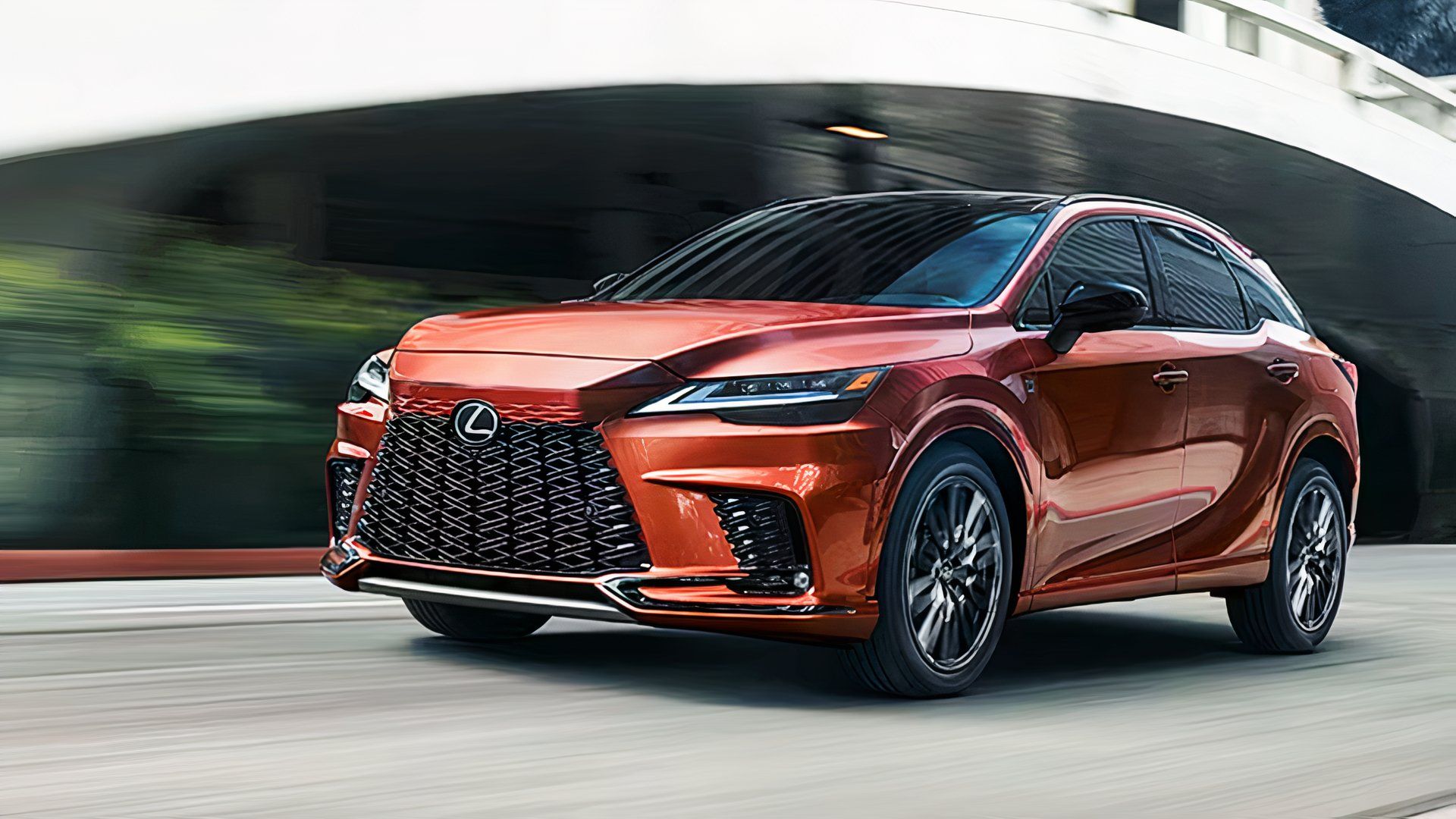 An orange 2025 Lexus RX Hybrid is driving.