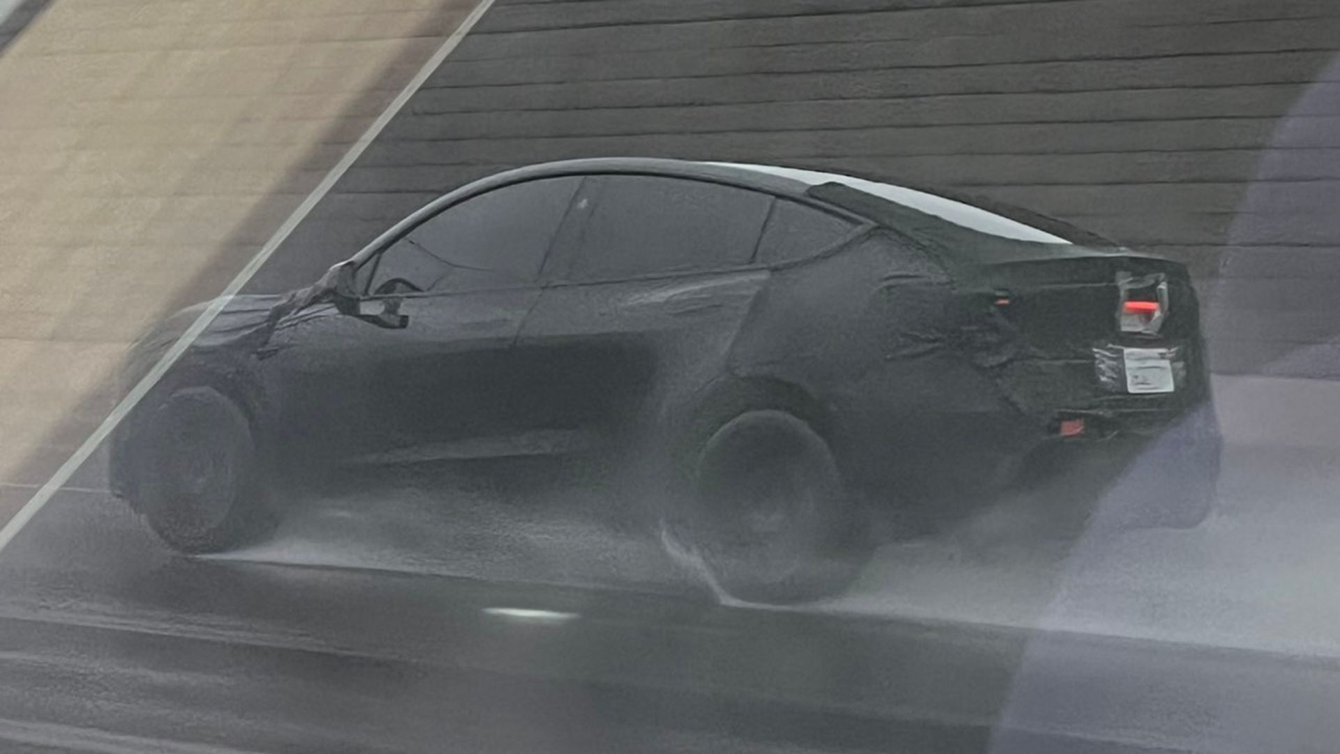 Photo of a Tesla Model Y Juniper prototype driving on the highway in the rain
