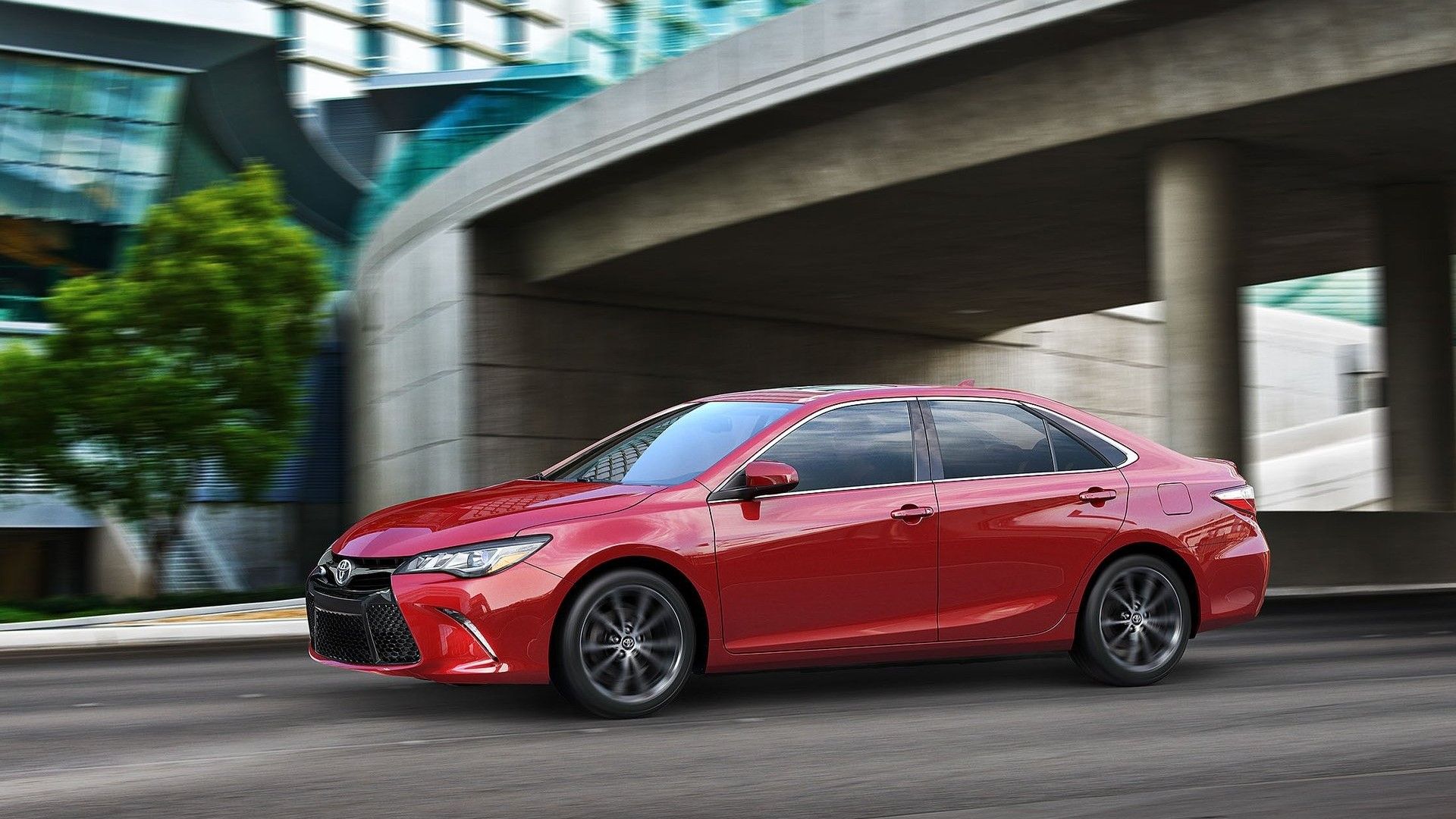 2015 Toyota Camry in red driving on city street