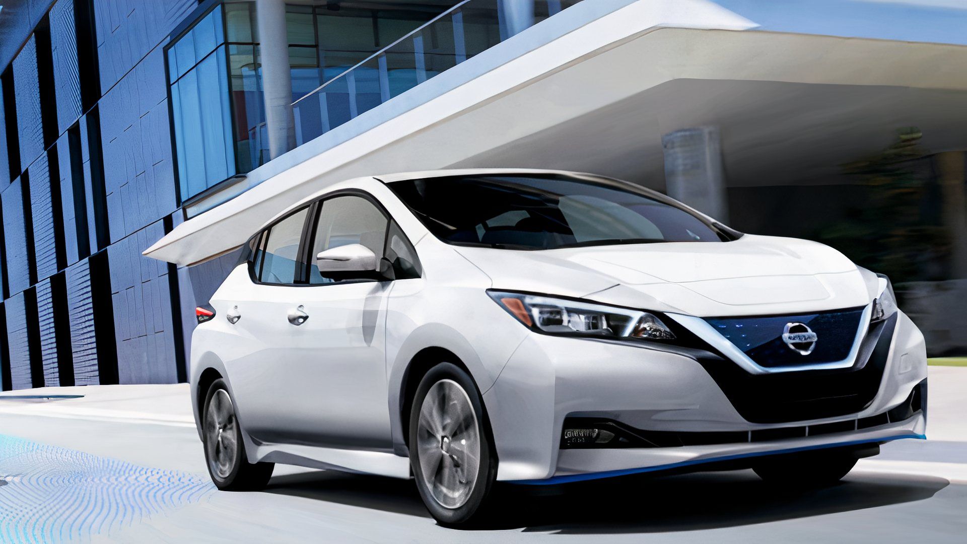 A white 2022 Nissan Leaf is driving on the road. 