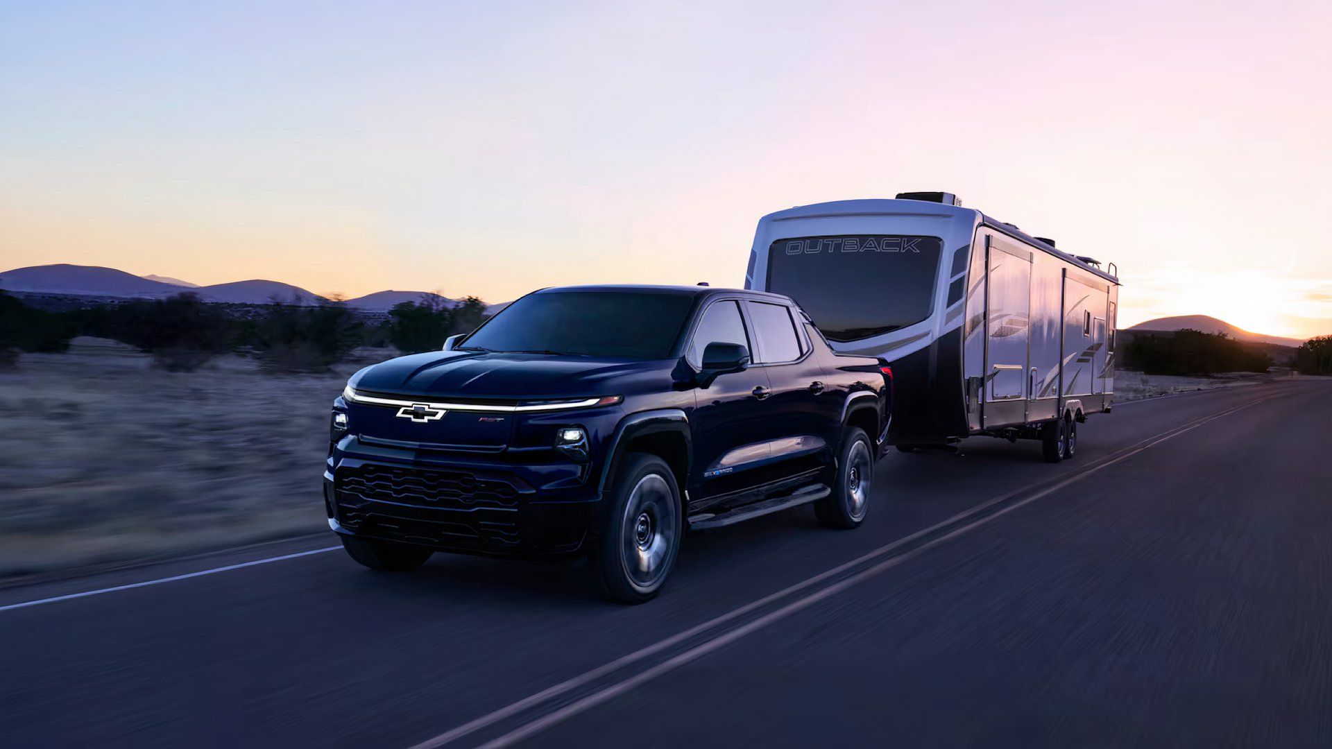 2025 Chevrolet Silverado EV in black towing caravan on road