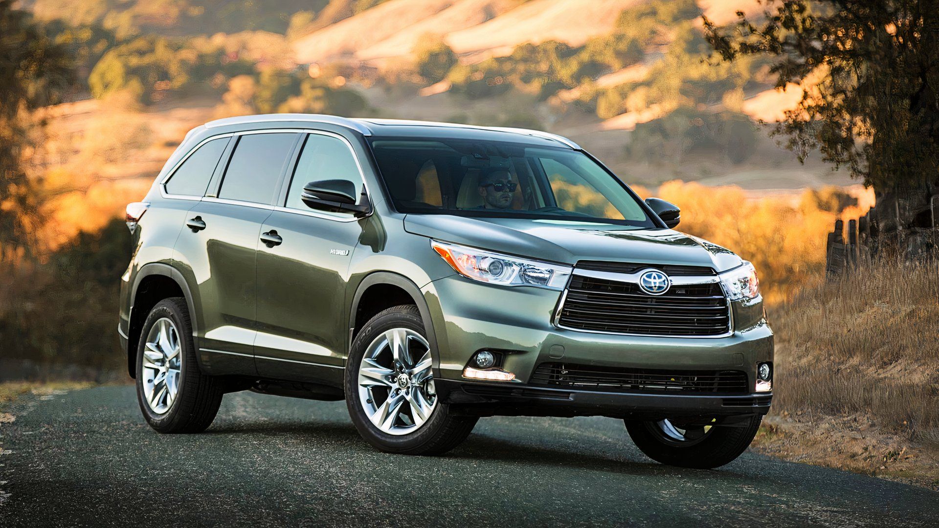 A green 2015 Toyota Highlander Hybrid midsize hybrid SUV. 