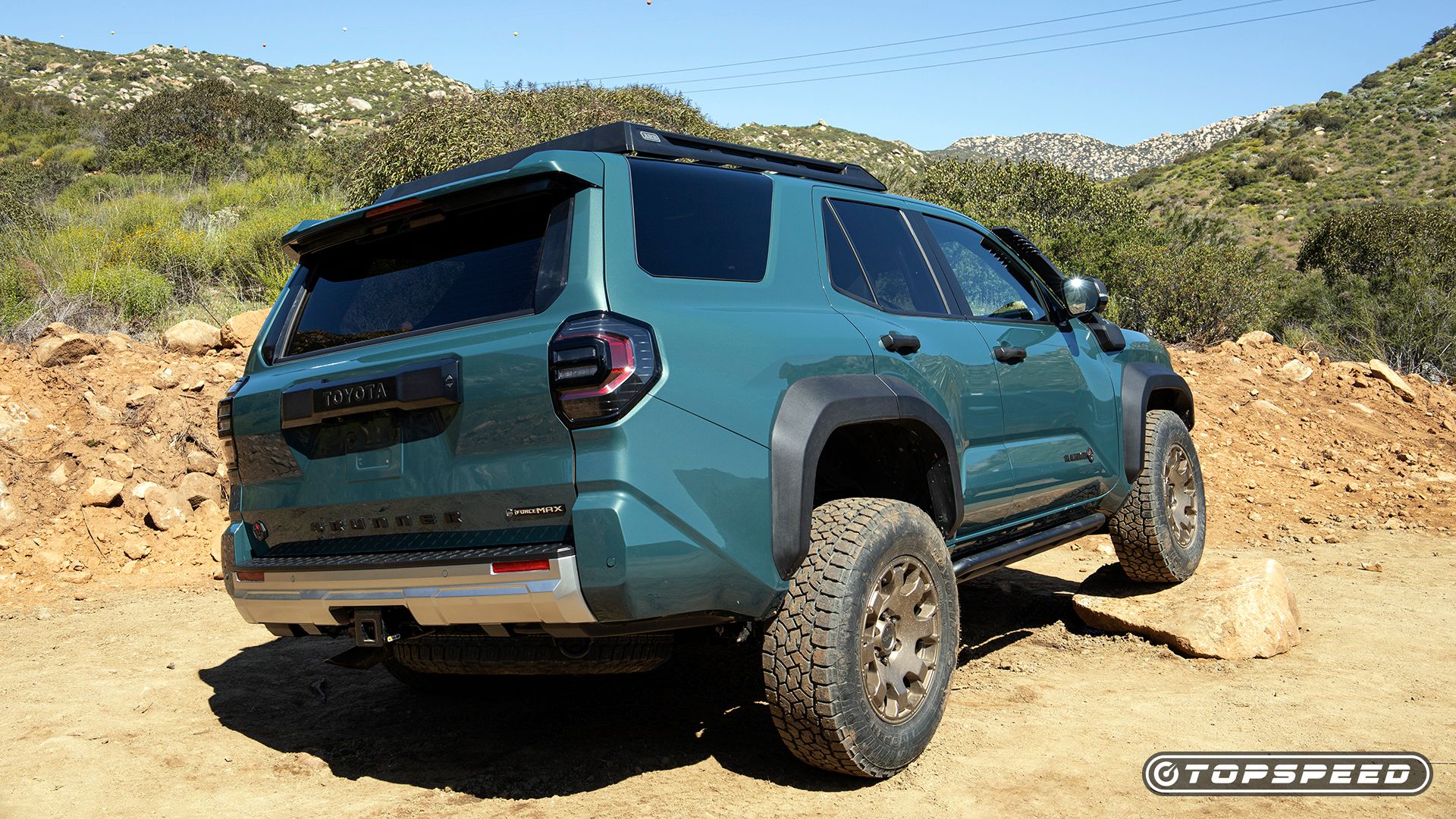 Rear three-quarters shot of a blue 2025 Toyota 4Runner climbing a rock