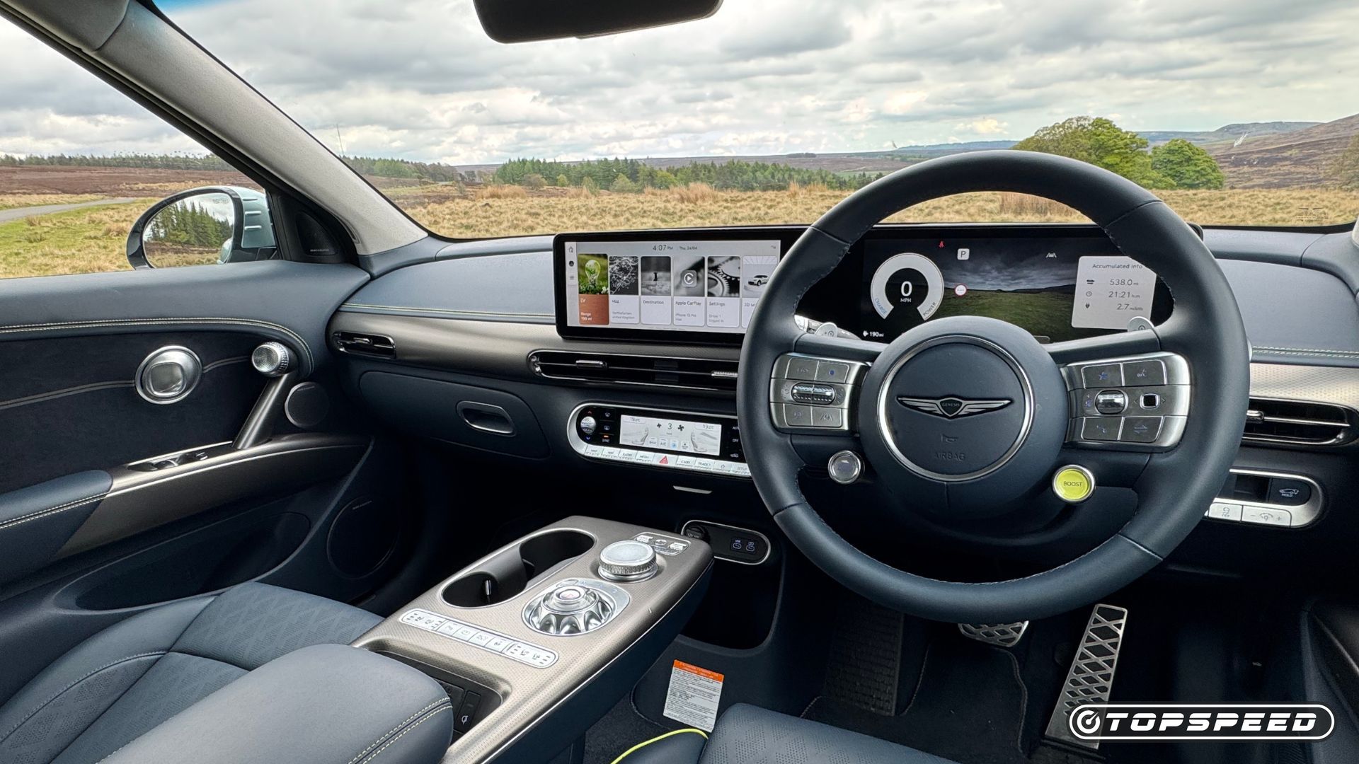 Close-up shot of the steering wheel and infotainment screen in a 2024 Genesis GV60 Sport Plus AWD.